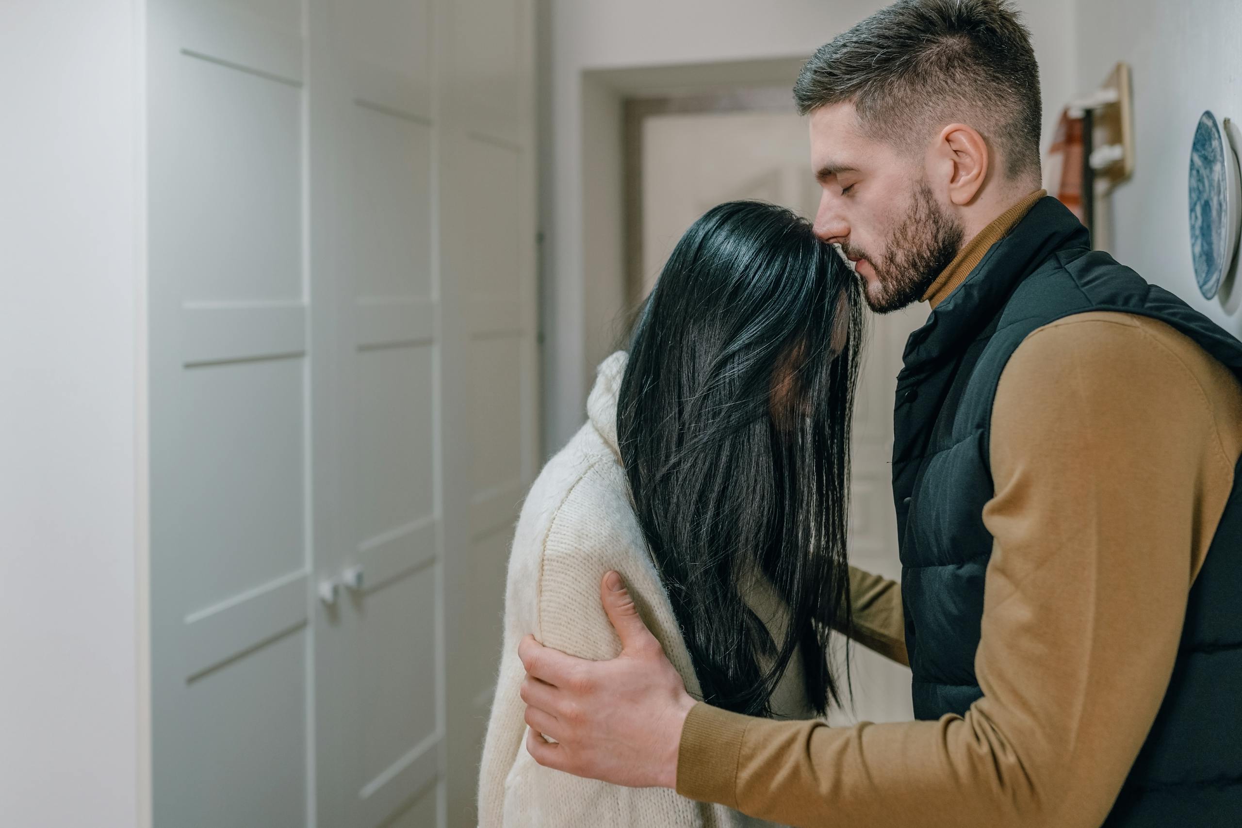 A couple shares a tender, intimate moment indoors, showcasing genuine emotion.
