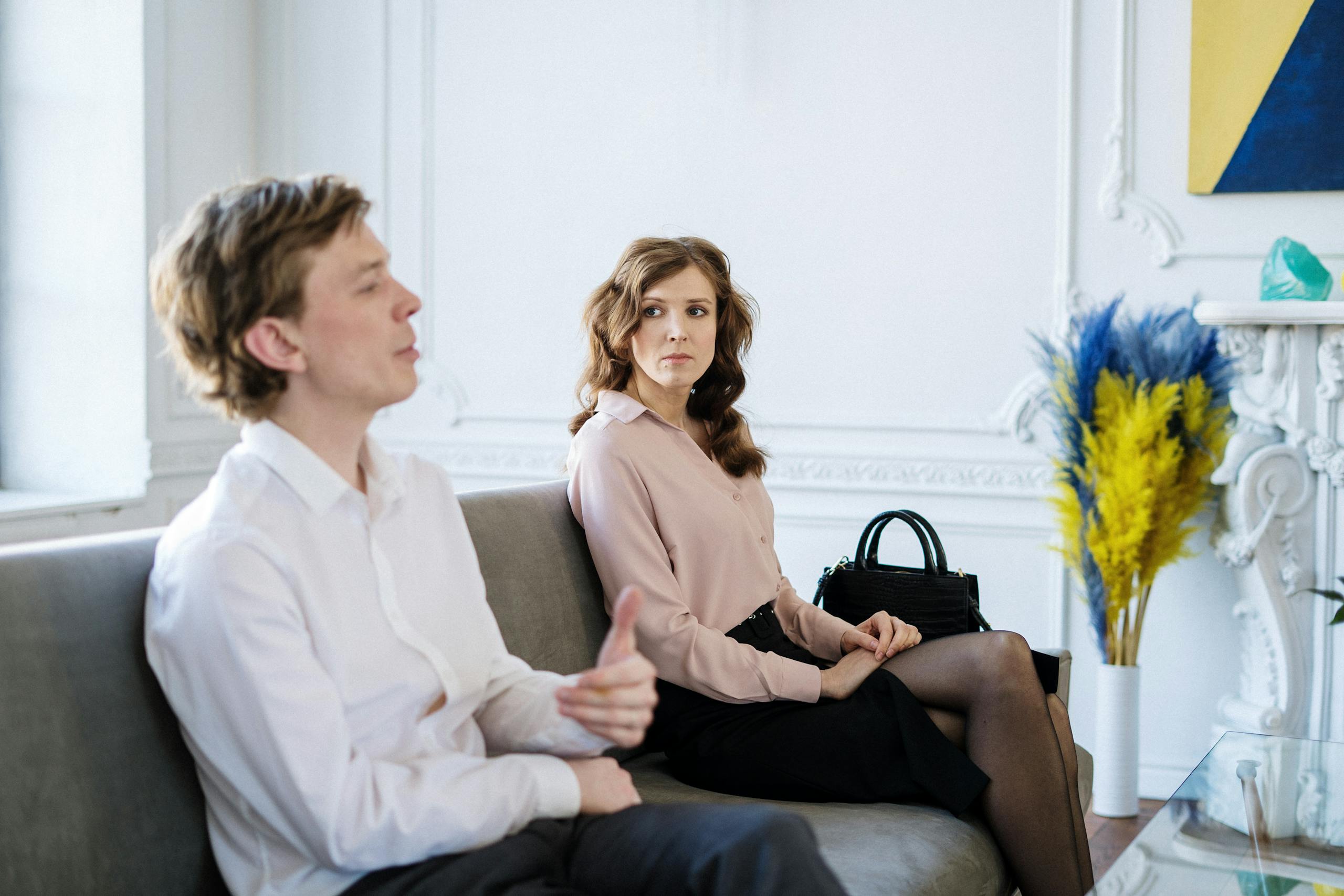 A couple sitting on a couch in a therapy session discussing relationship concerns.