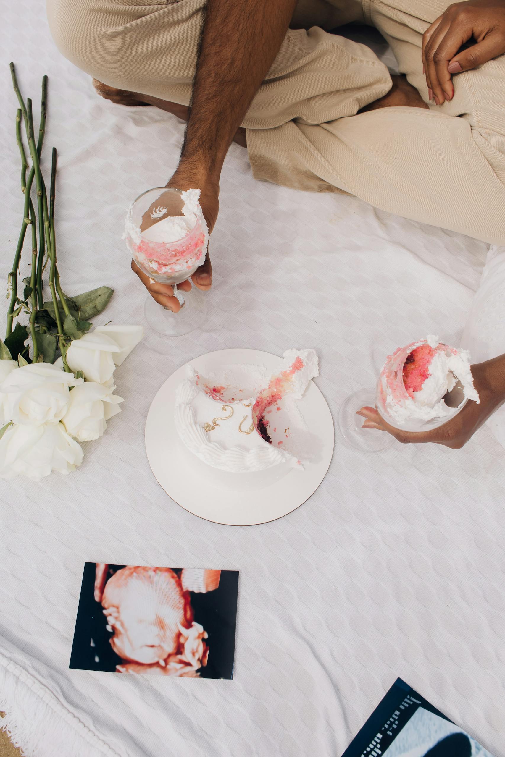 A cozy outdoor picnic scene with cake, roses, and ultrasound photo for a special celebration.