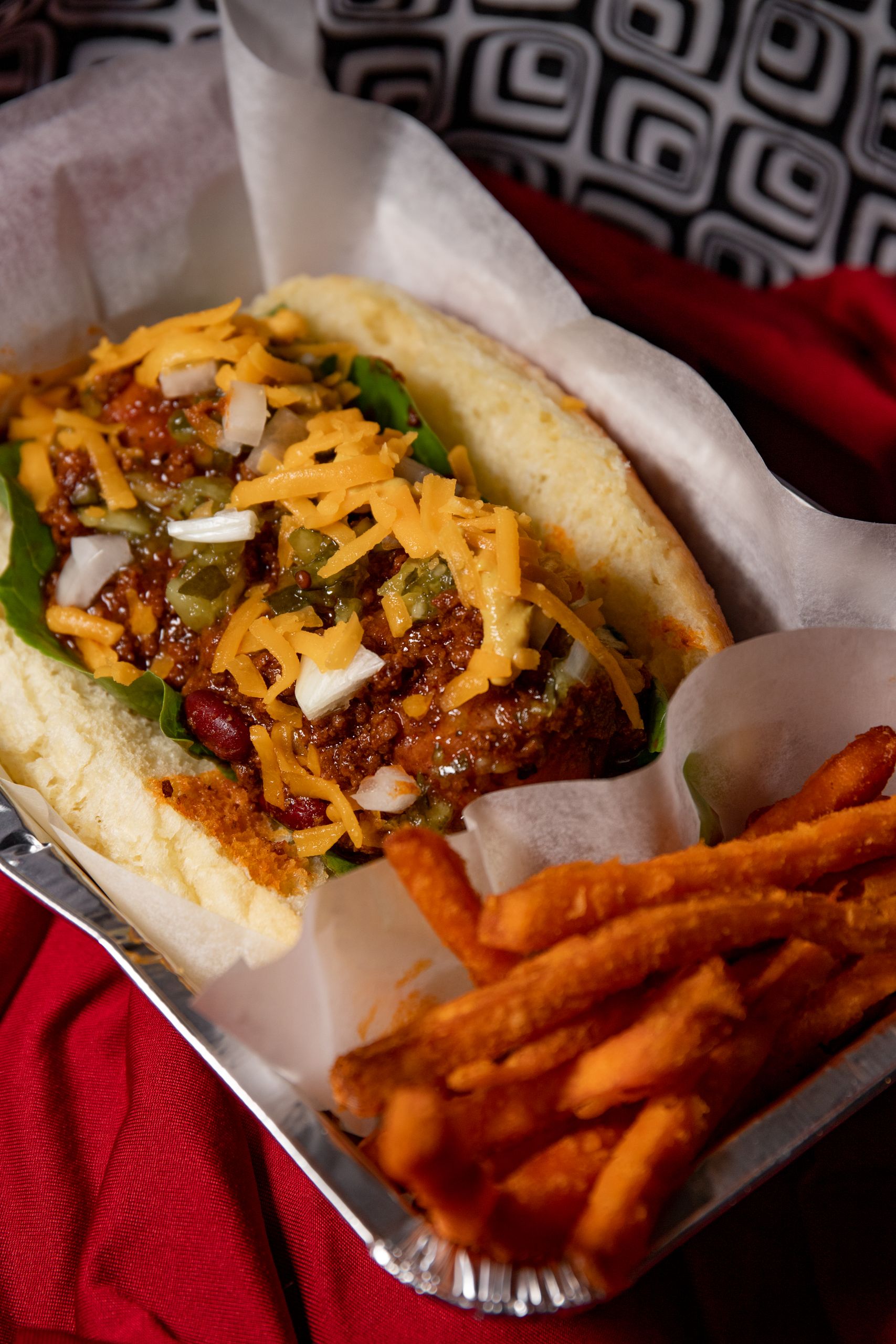 A delicious chili cheese hot dog served with crispy sweet potato fries.