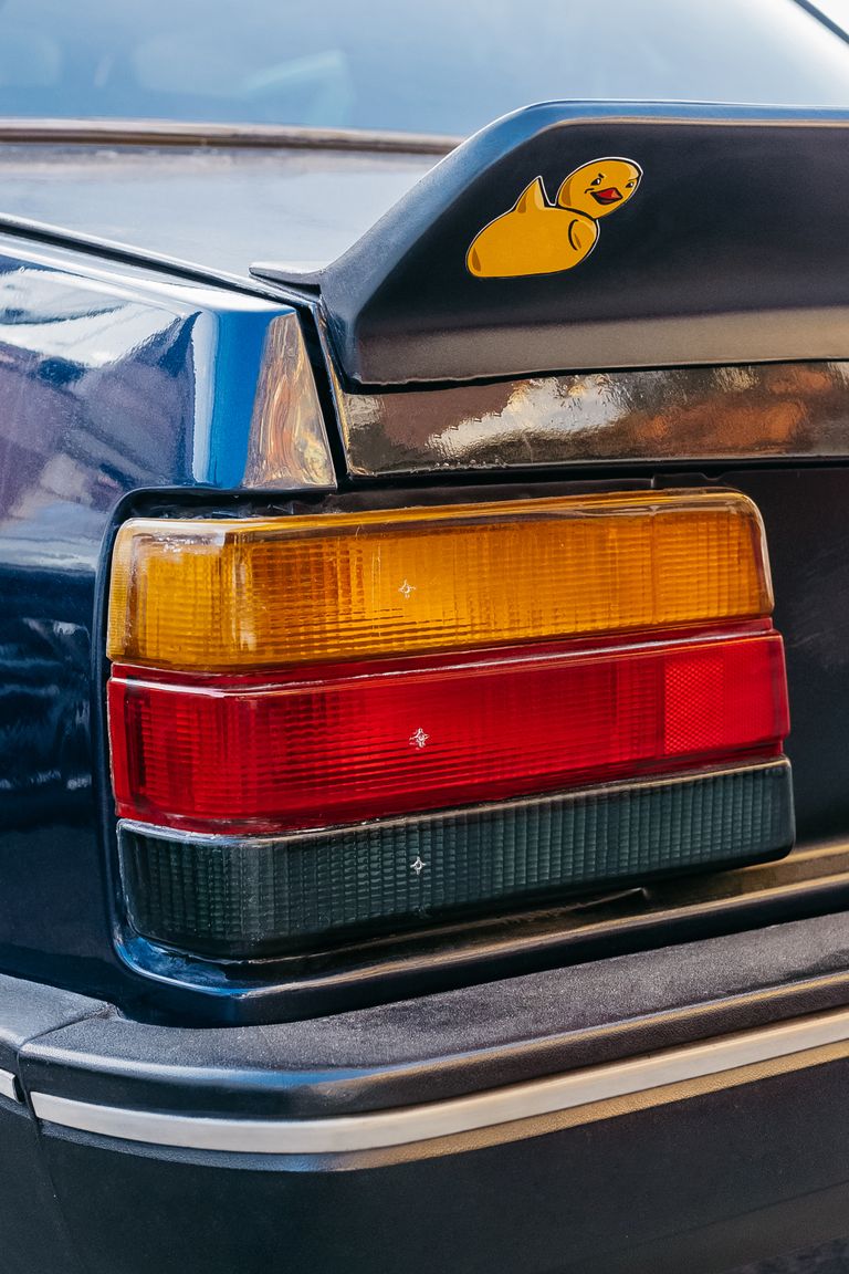 A detailed view of a classic car's rear lights and a duck sticker on the spoiler.
