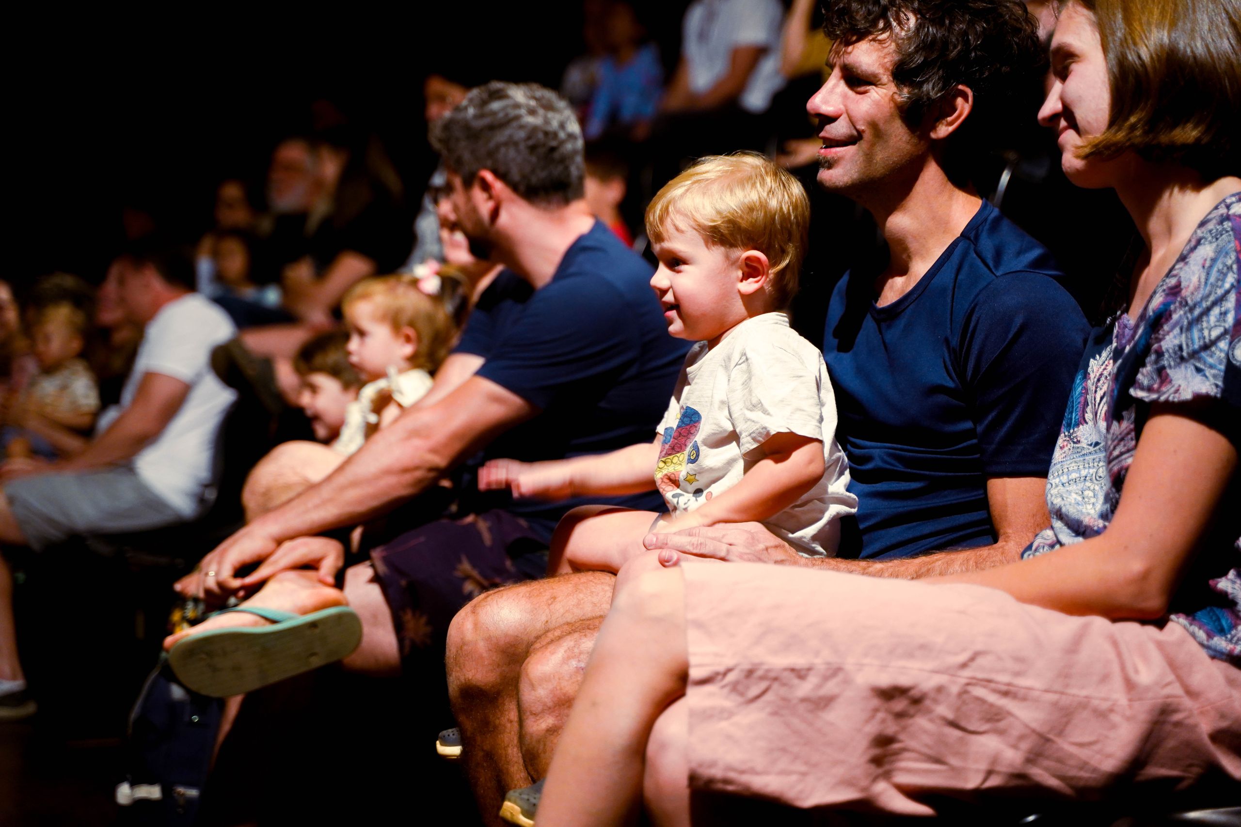 A diverse audience, including families, enjoys a live performance in a Brasil theater.
