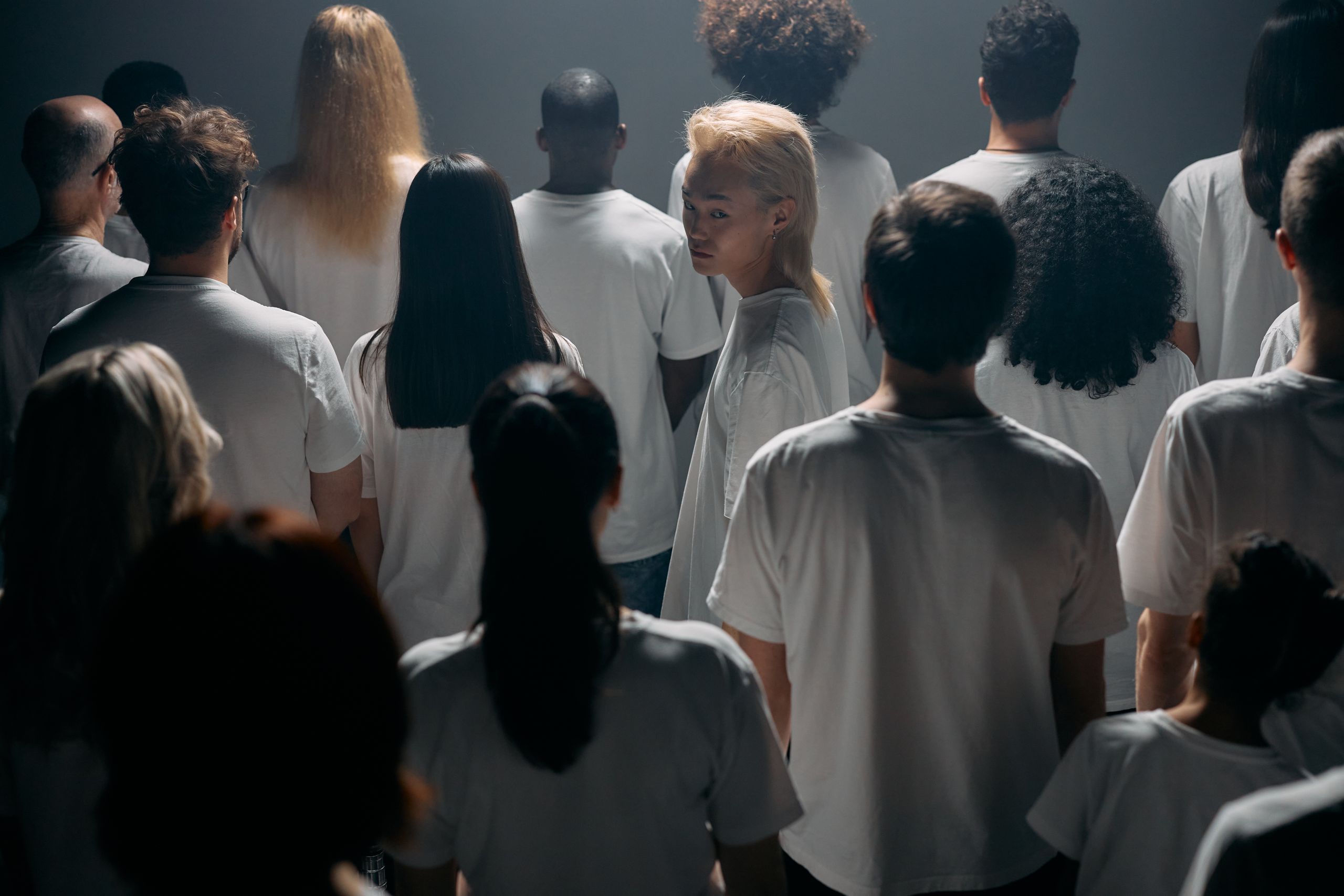 A diverse crowd stands together in a studio, exploring themes of individuality and social connections.