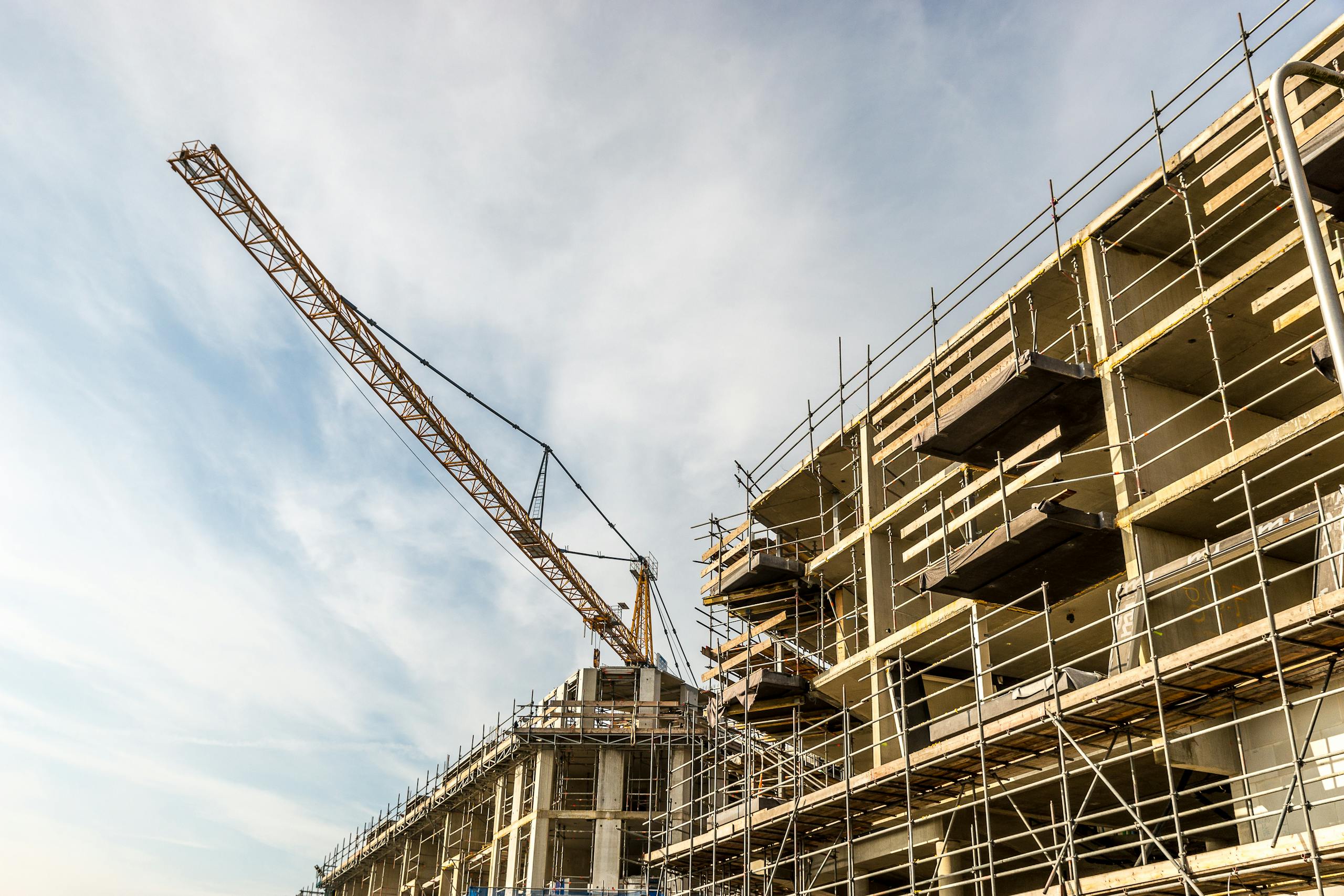 A dynamic view of a construction site with crane and scaffolding on a sunny day.