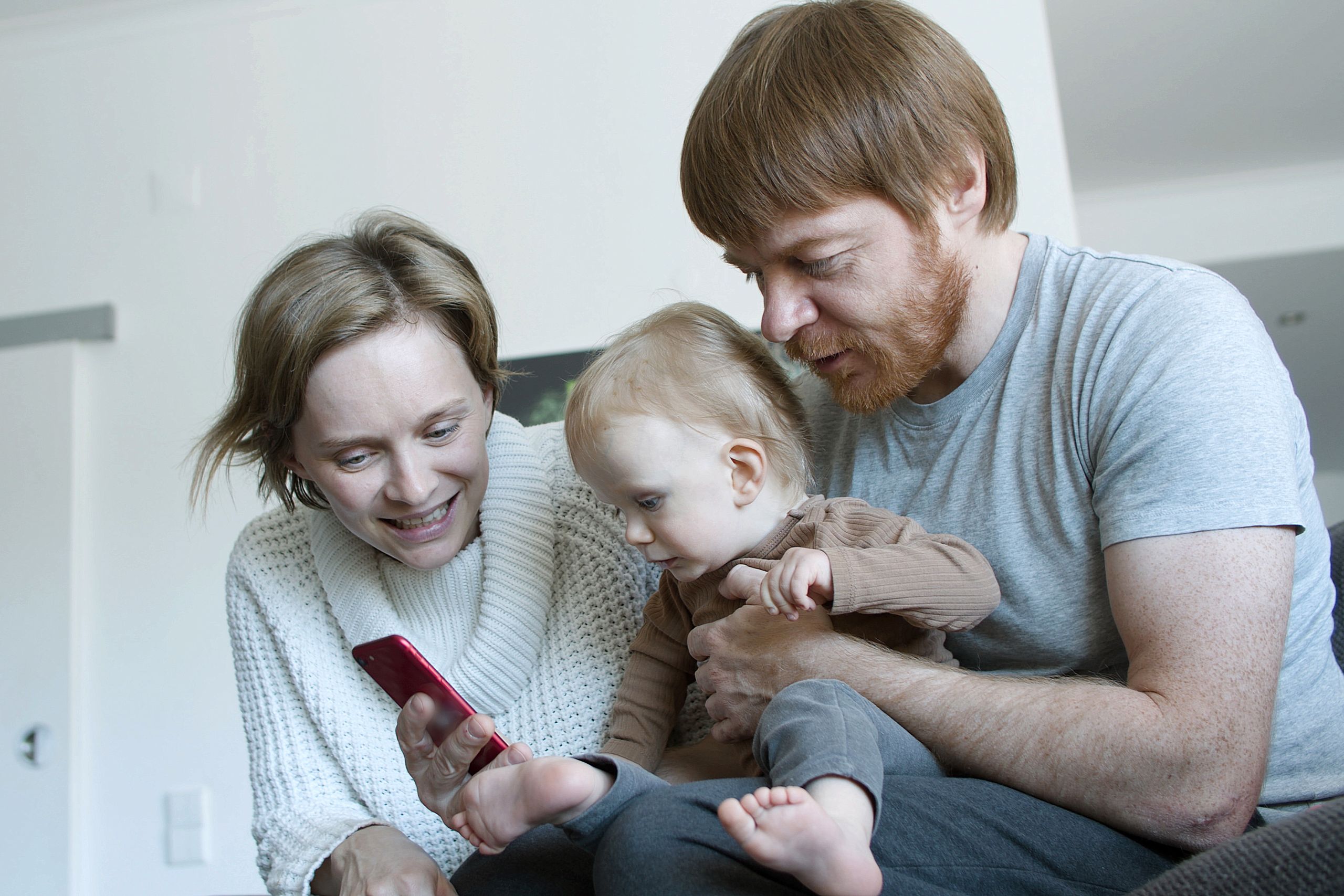 A family enjoying quality time together at home, interacting with a smartphone.