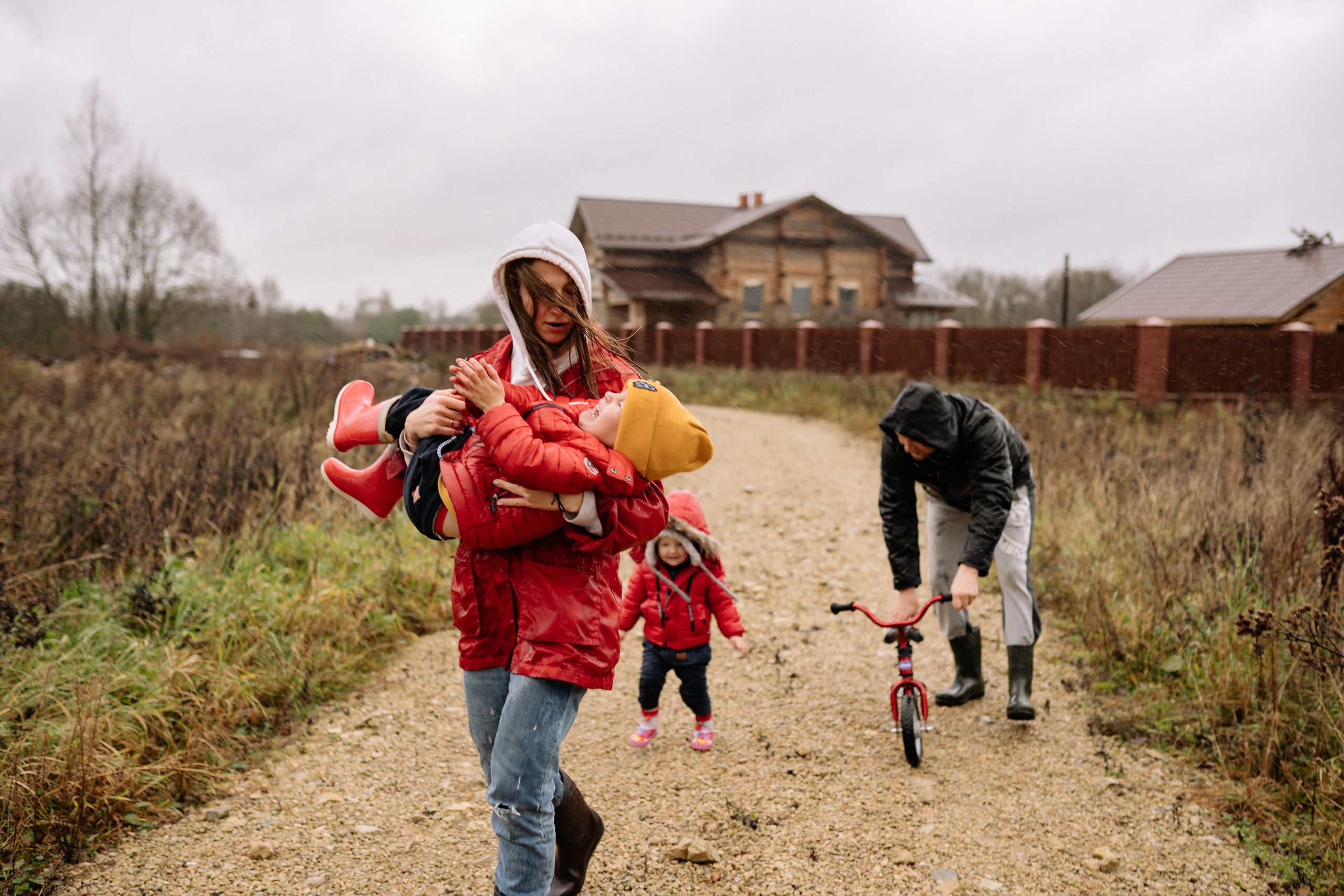 A family enjoys a walk in the countryside on a rainy day, highlighting quality time and connection.