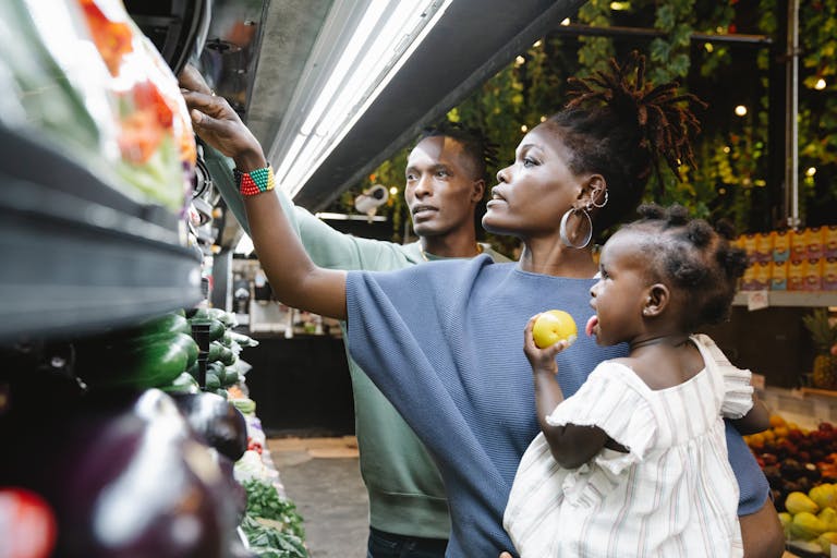 A family of three shopping in a grocery store, selecting fresh produce together.