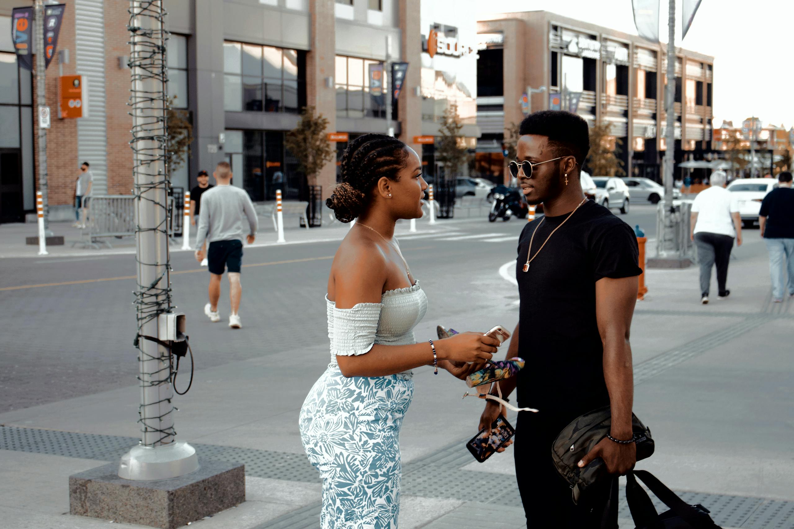 A fashionable couple converses on a busy urban street in Canada, showcasing modern style.