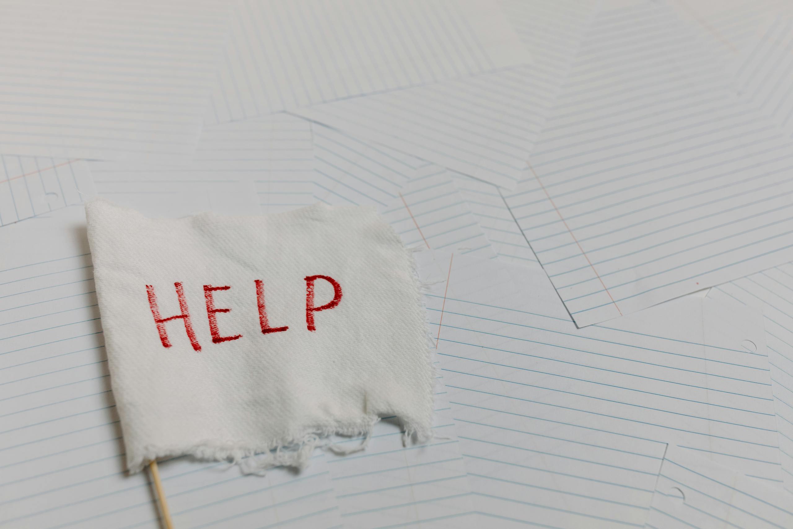 A flag with 'HELP' text on a lined paper background signifying distress or need for assistance.