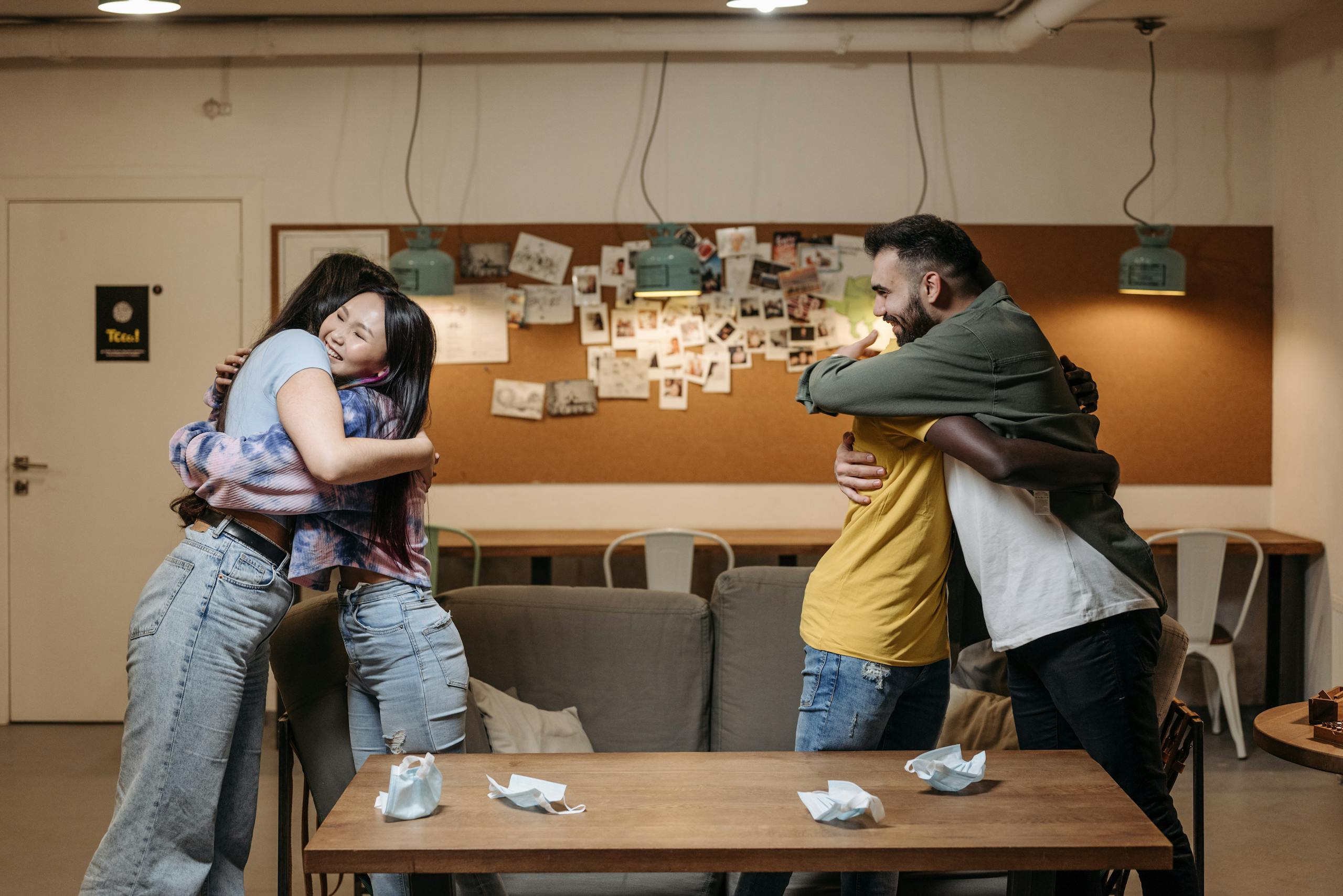 A group of diverse friends happily hugging in a cozy indoor setting, showcasing togetherness.