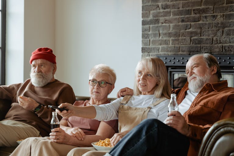 A group of senior adults relaxing and watching TV together in a cozy living room.