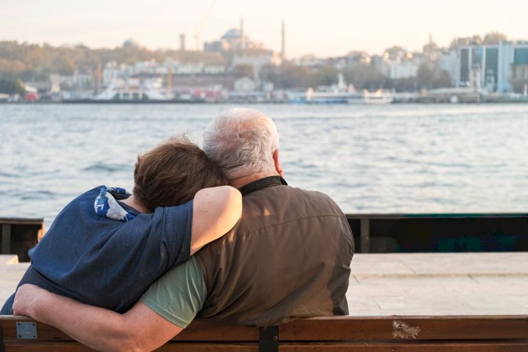 A heartfelt moment of an elderly couple embracing by the Bosphorus in Istanbul, capturing the city's charm.