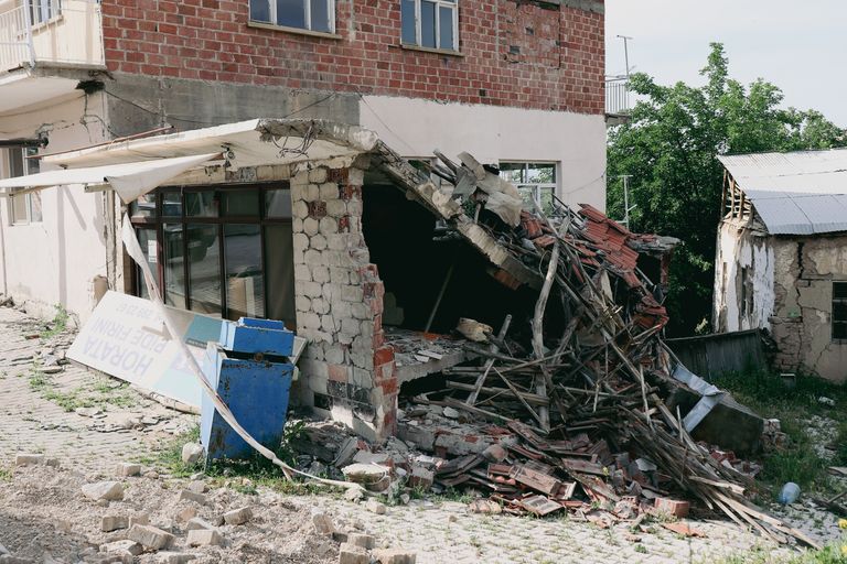 A heavily damaged building exterior, showing structural collapse post-earthquake.