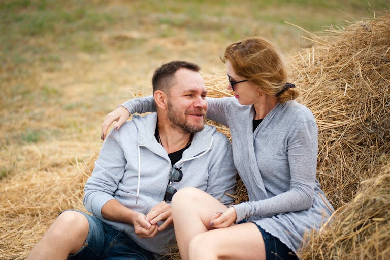 A joyful couple embraces in a sunlit field, enjoying summer leisure time together.
