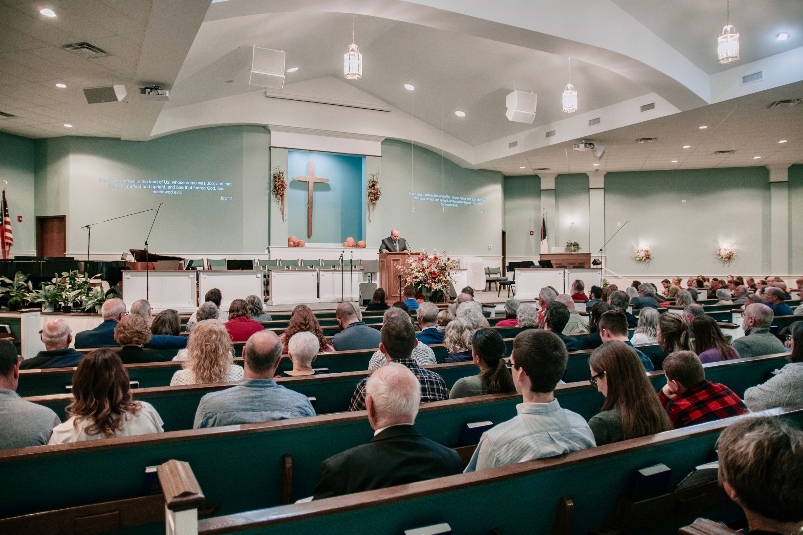 A large congregation listens to a speaker in a modern church setting.