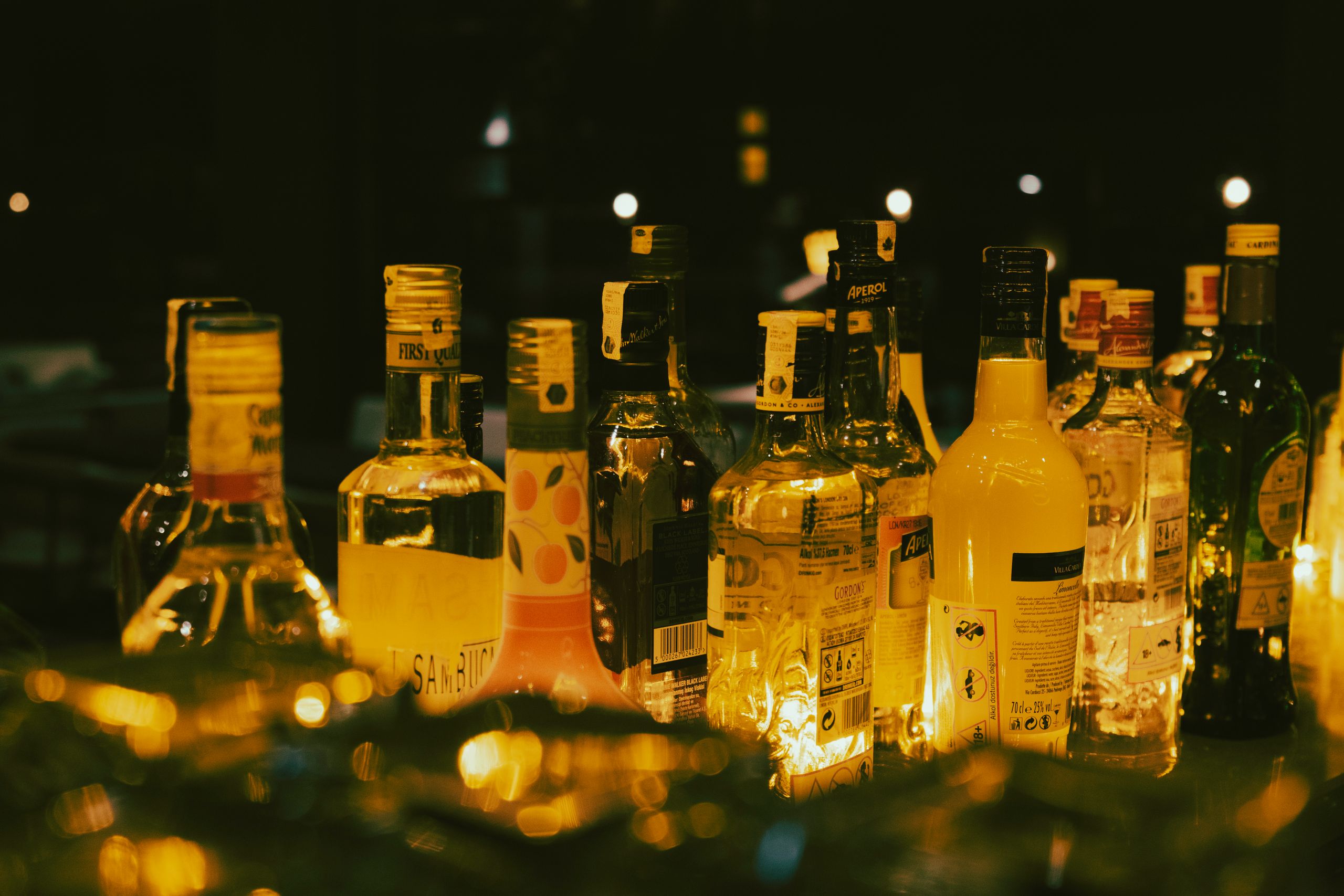 A lively close-up of assorted alcohol bottles illuminated in a dimly lit setting, creating a vibrant atmosphere.
