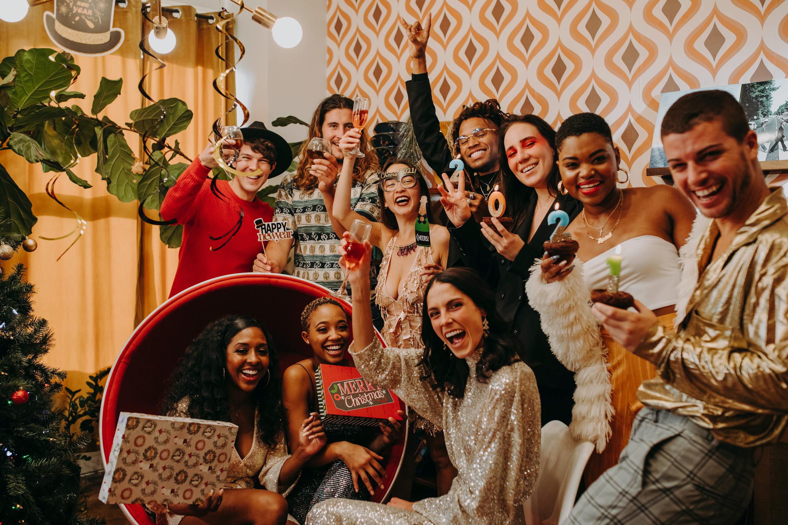 A lively party scene with a diverse group celebrating New Year's Eve indoors with drinks and decorations.