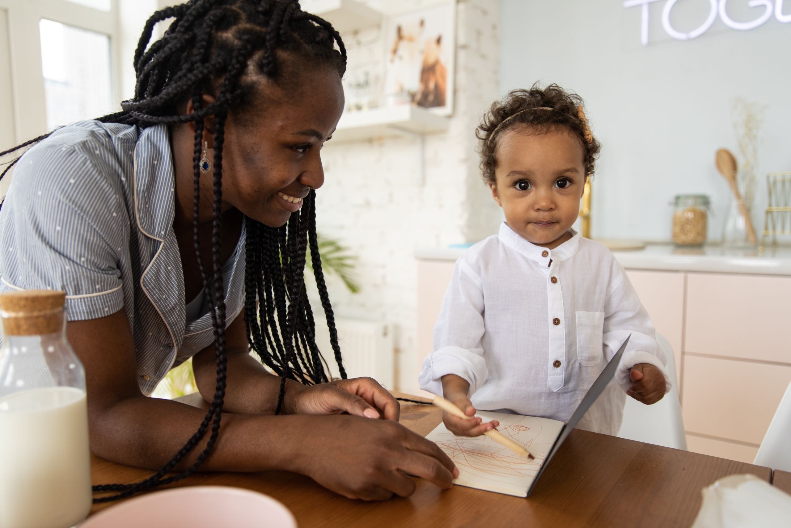 A loving mother and her child engage in a drawing activity at the table.