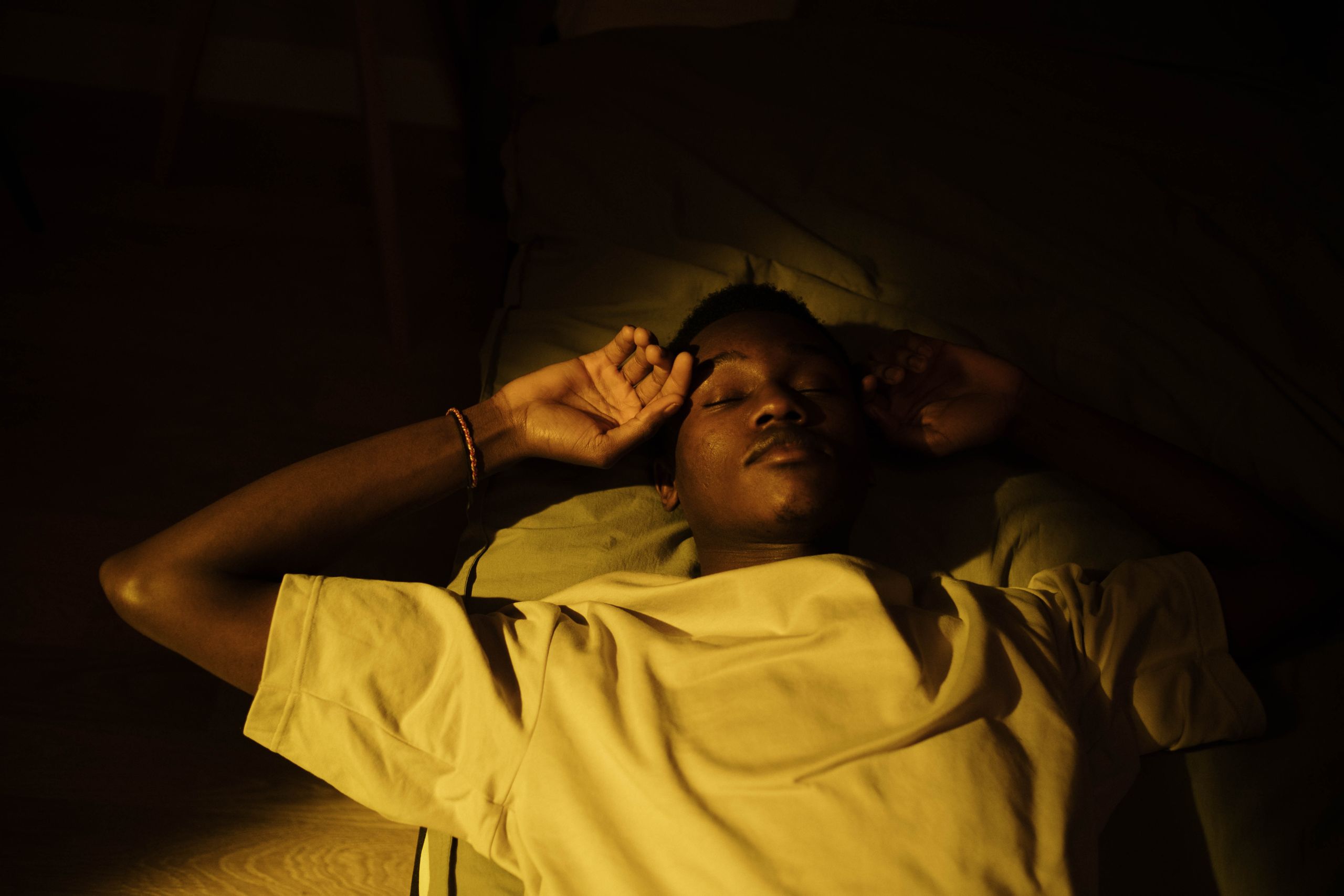 A man lying down in a cozy, warm-lit room, peacefully asleep during the night.