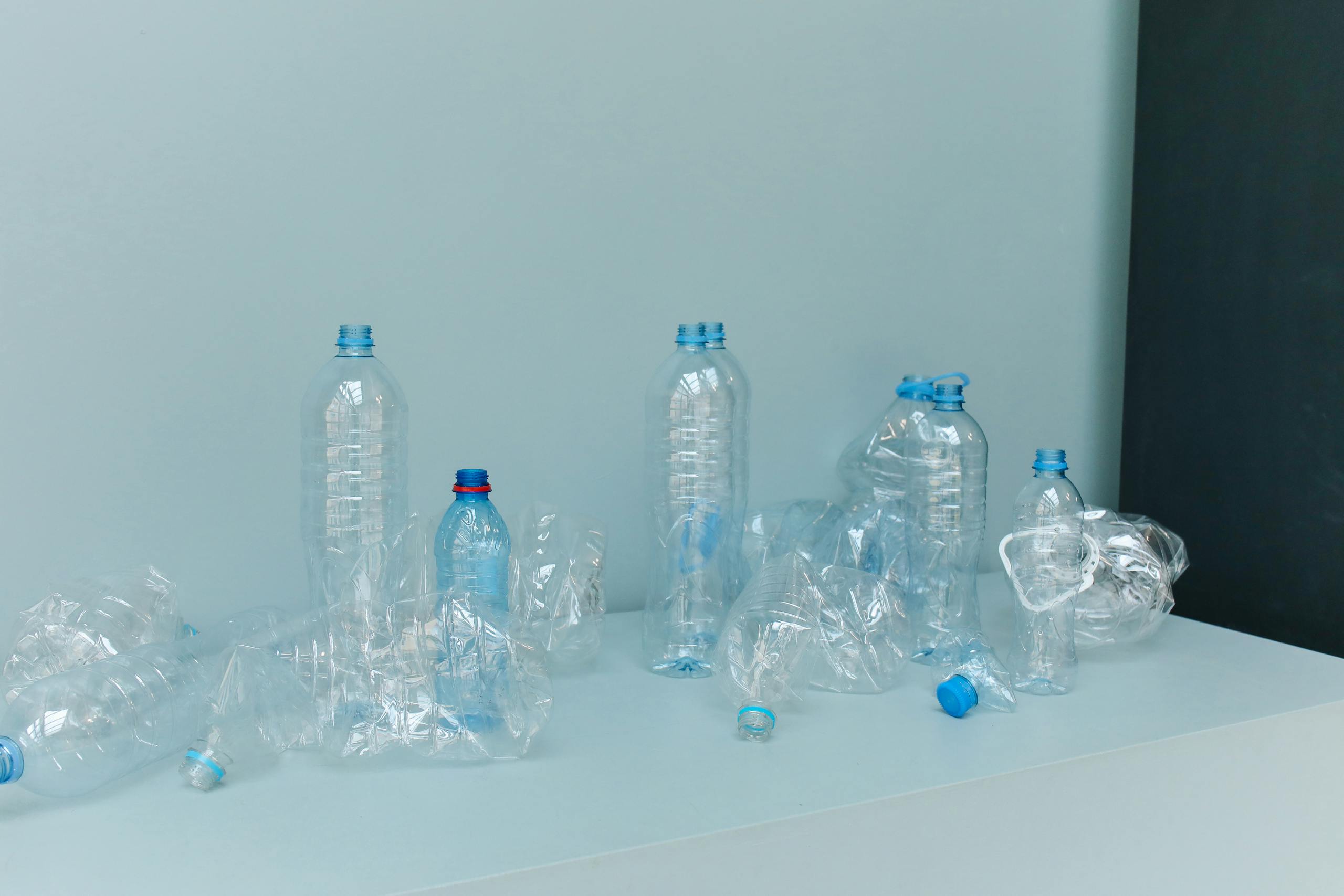 A minimalist still life of empty plastic bottles on a white surface, promoting environmental awareness.