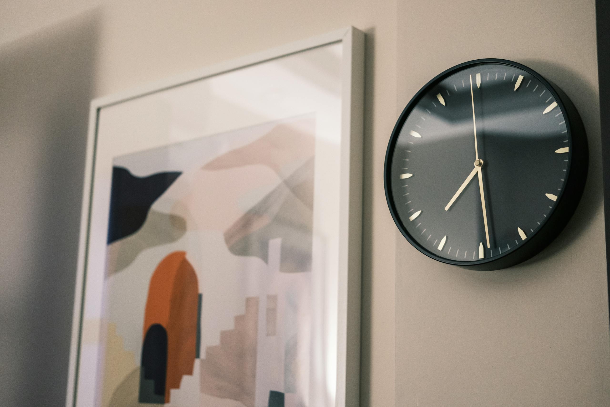 A minimalist wall clock and abstract painting in a modern interior setting.