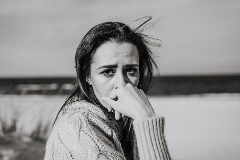 A monochrome portrait of a woman with pensive expression at the beach.