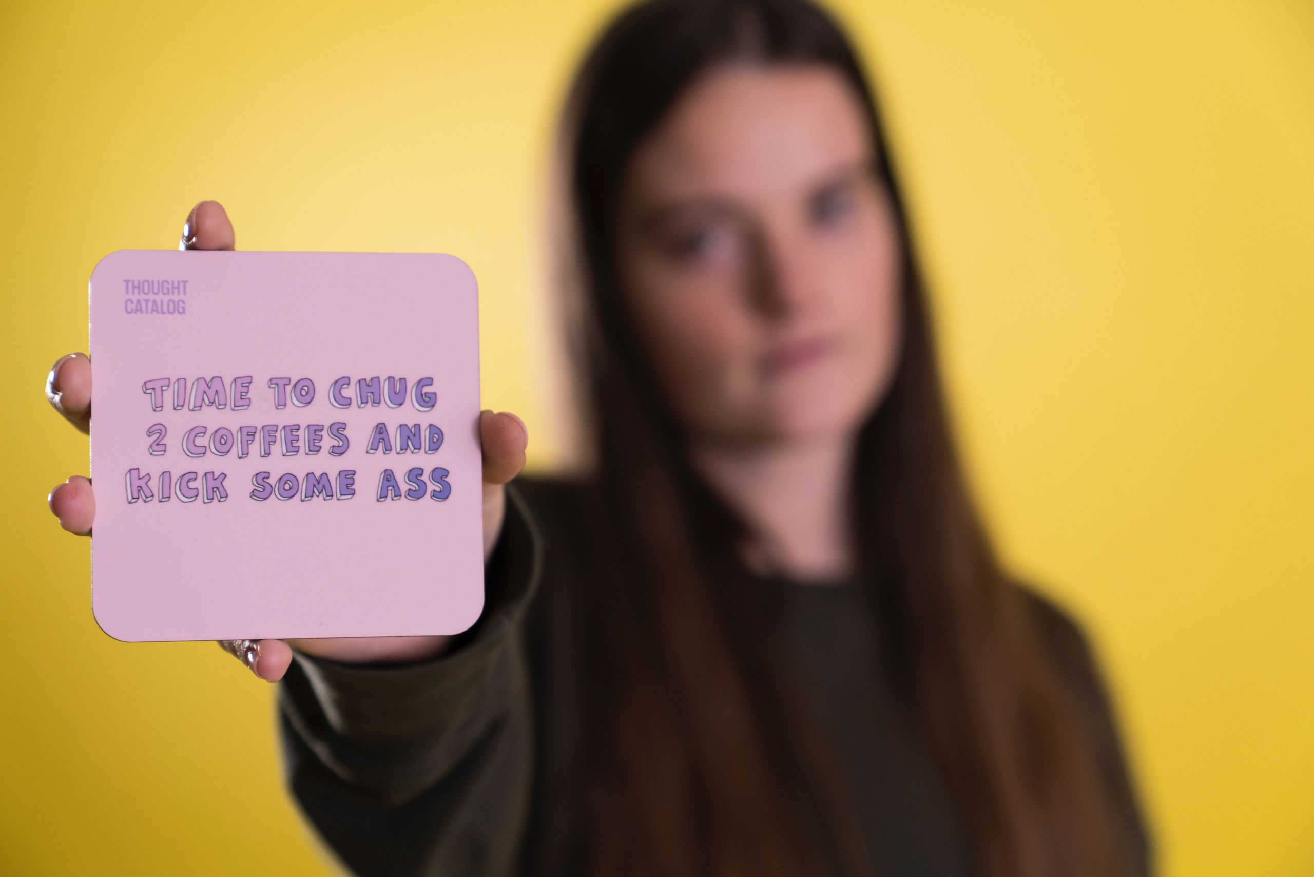 A motivational quote on a pink card held by a woman with a yellow background.