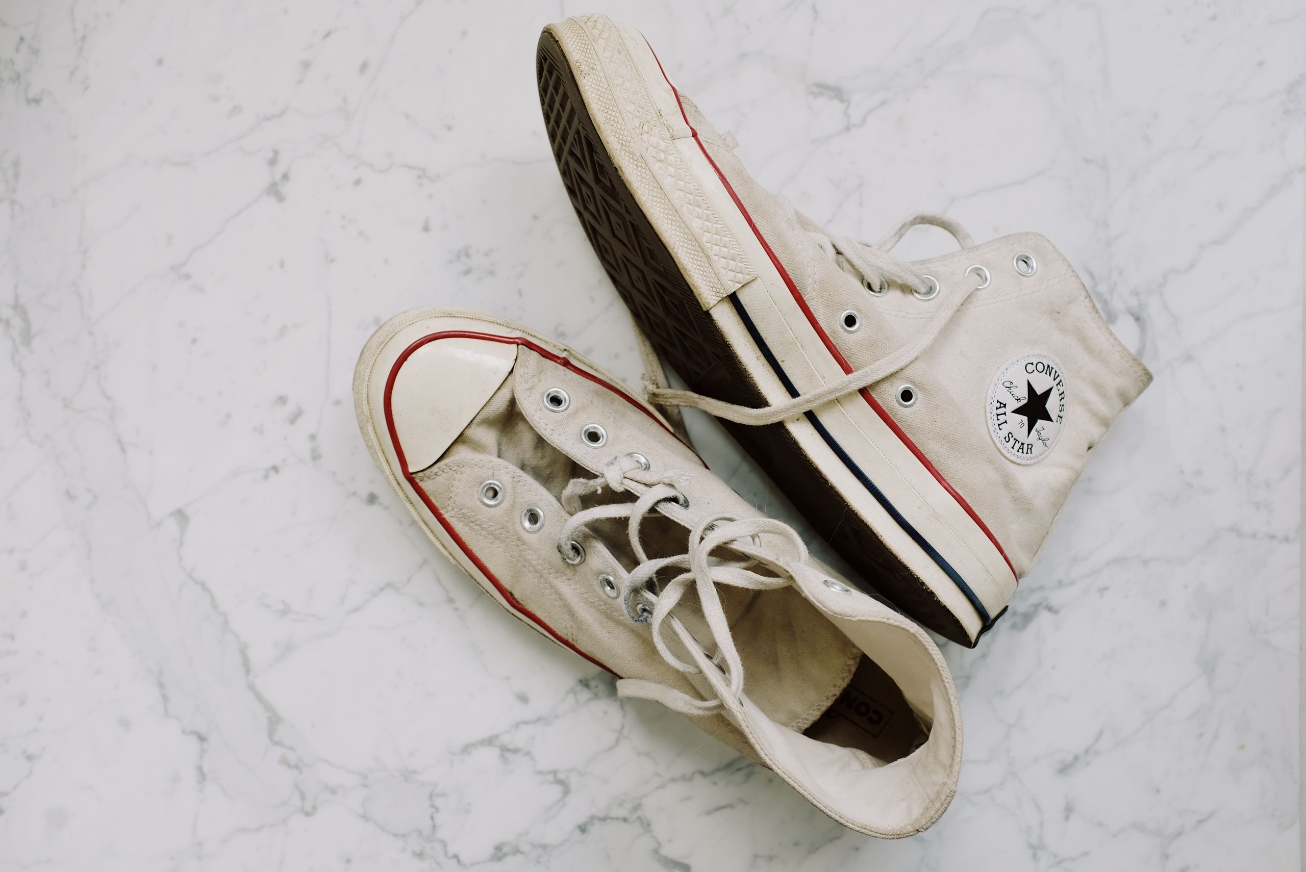 A pair of dirty Converse All Star sneakers on a marble surface. Fashionable and vintage style footwear.