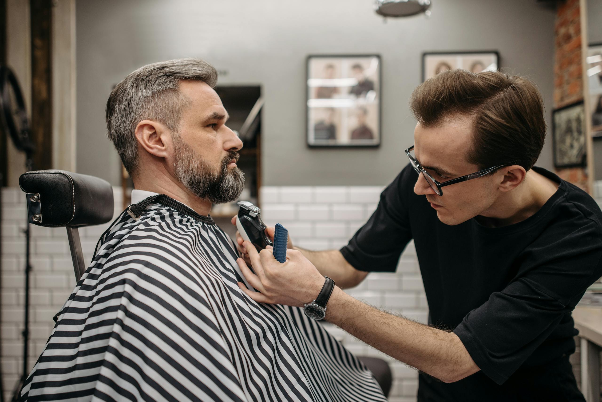 A professional barber precisely trimming a client's beard in a modern barbershop.