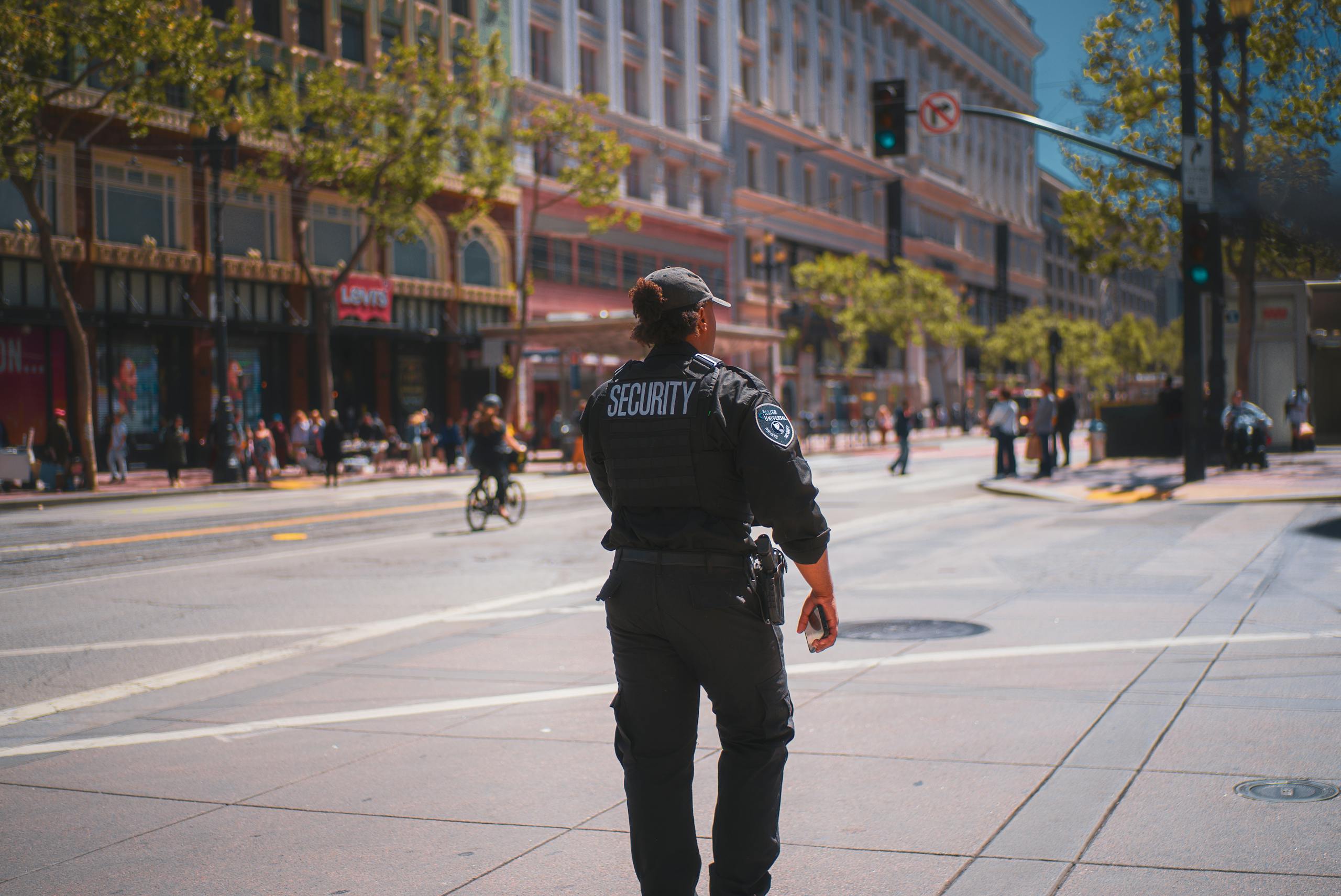 A security officer patrols a bustling street in San Francisco, capturing daily urban life.