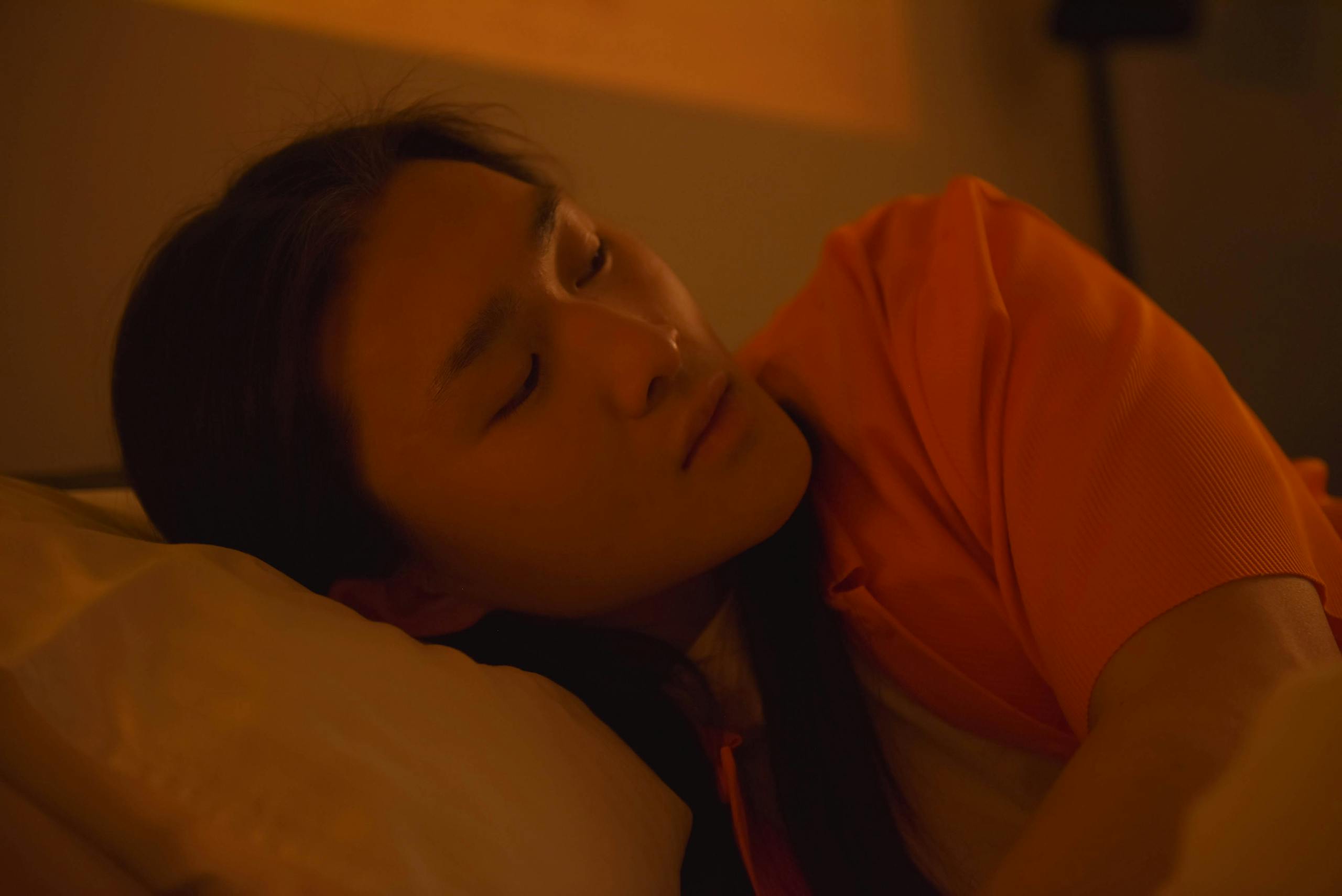 A serene moment of an Asian woman lying down indoors, reflecting tranquility and rest.