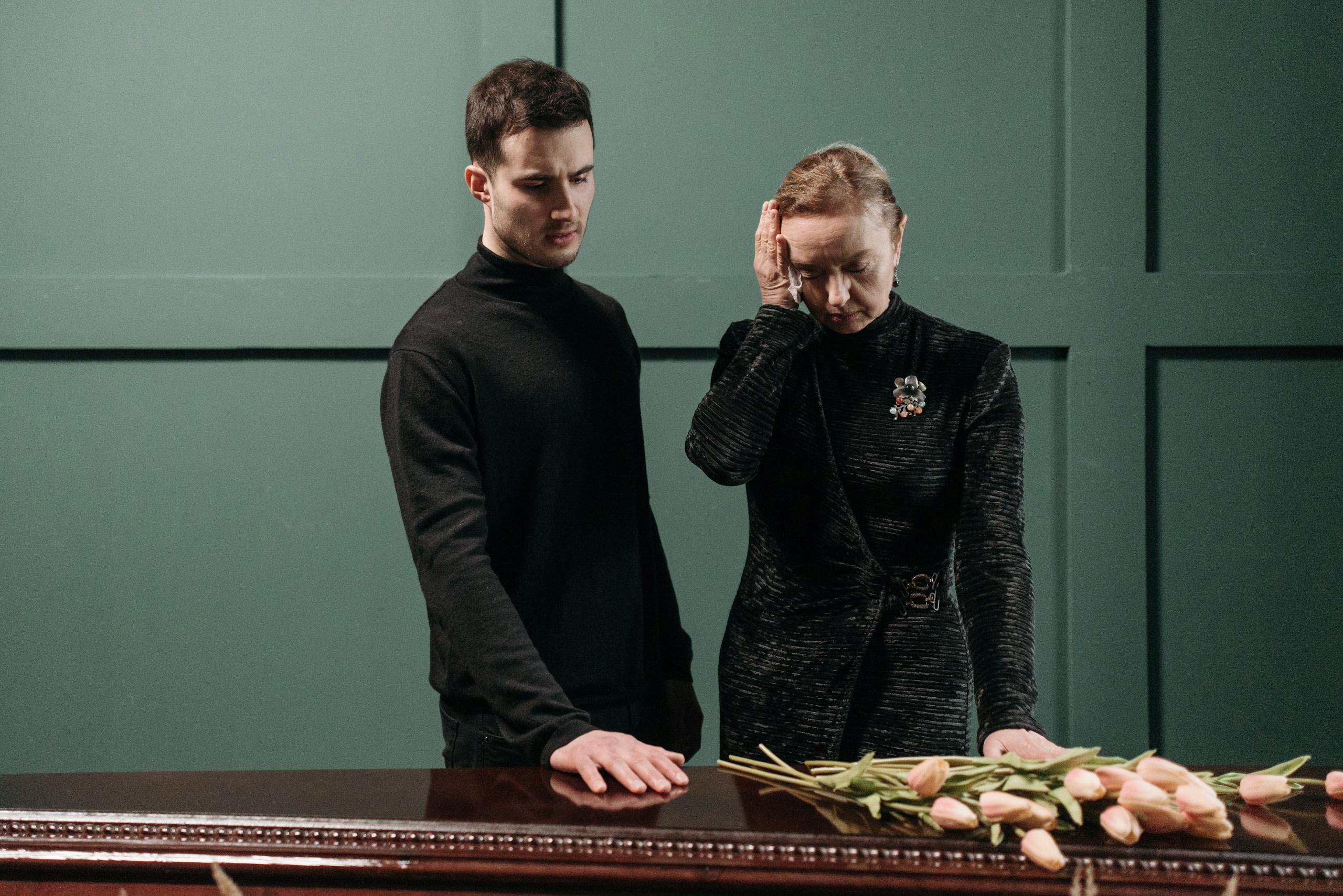 A solemn moment shared between a man and woman at a funeral, symbolizing loss and mourning.