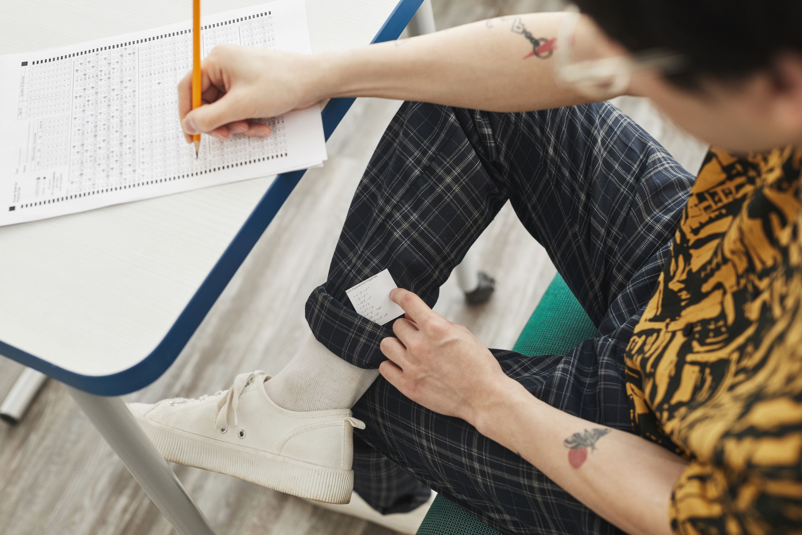 A student using hidden notes to cheat during an exam, showcasing academic dishonesty.