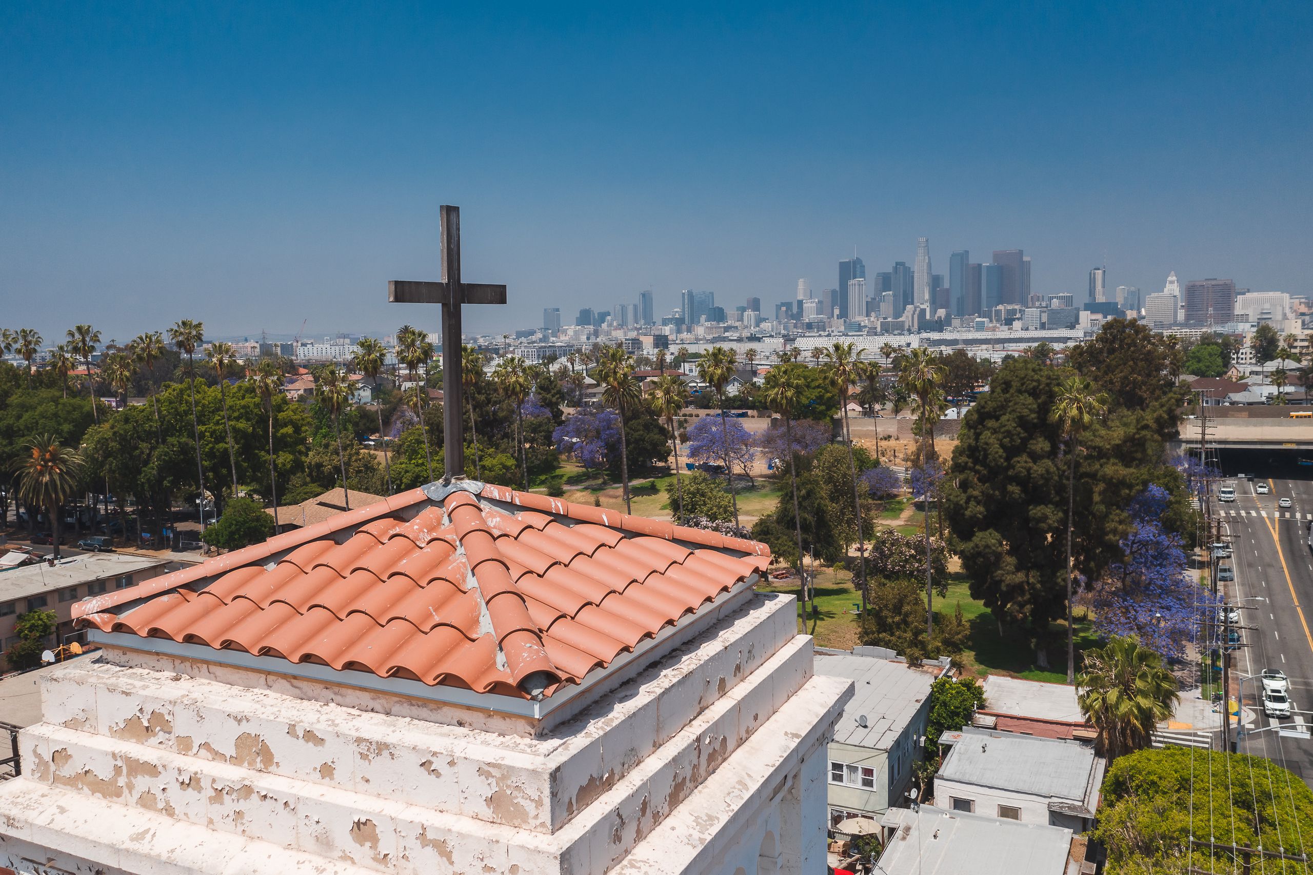 A stunning aerial view of a church roof overlooking the vibrant Los Angeles skyline under a clear blue sky.