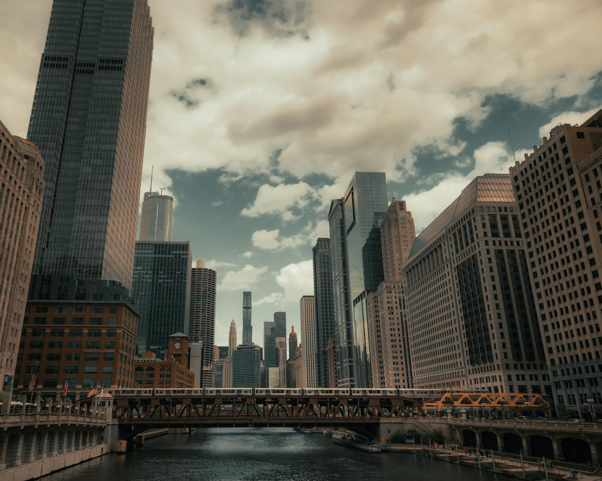 A stunning view of Chicago's skyline and river with prominent skyscrapers and bridges on a cloudy day.