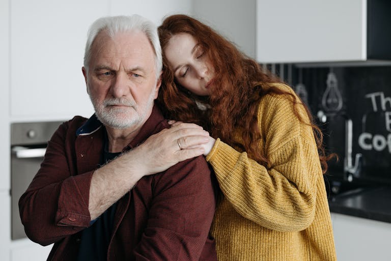 A touching scene of a grandfather and granddaughter sharing an emotional moment indoors.