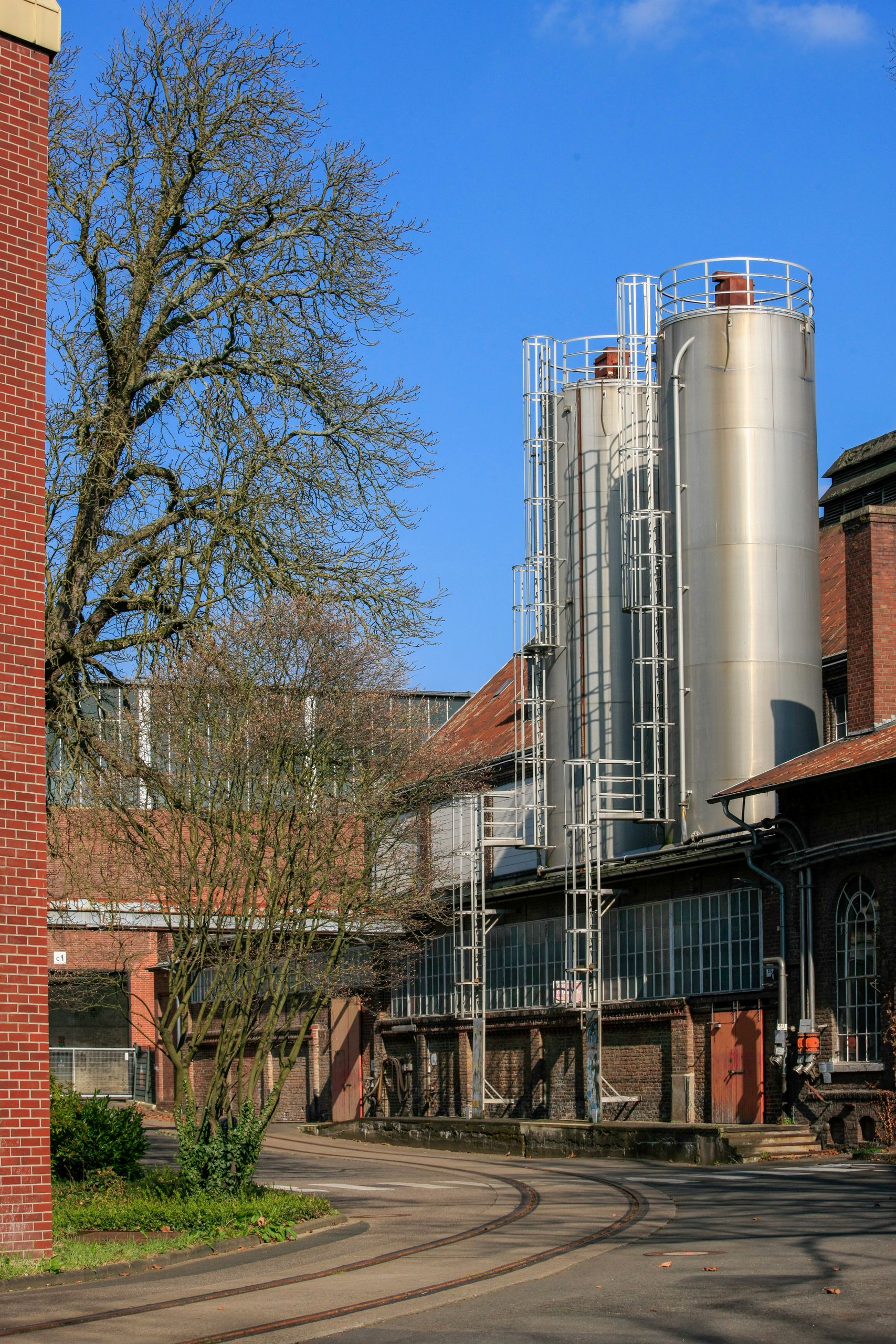 A traditional industrial facility with tall silos and brick buildings under a clear blue sky.