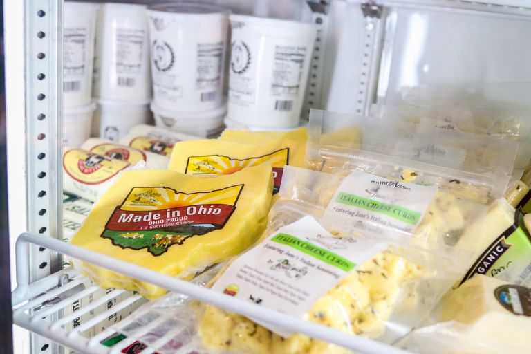 A variety of fresh Ohio cheeses displayed in a store refrigerator, showcasing local produce.