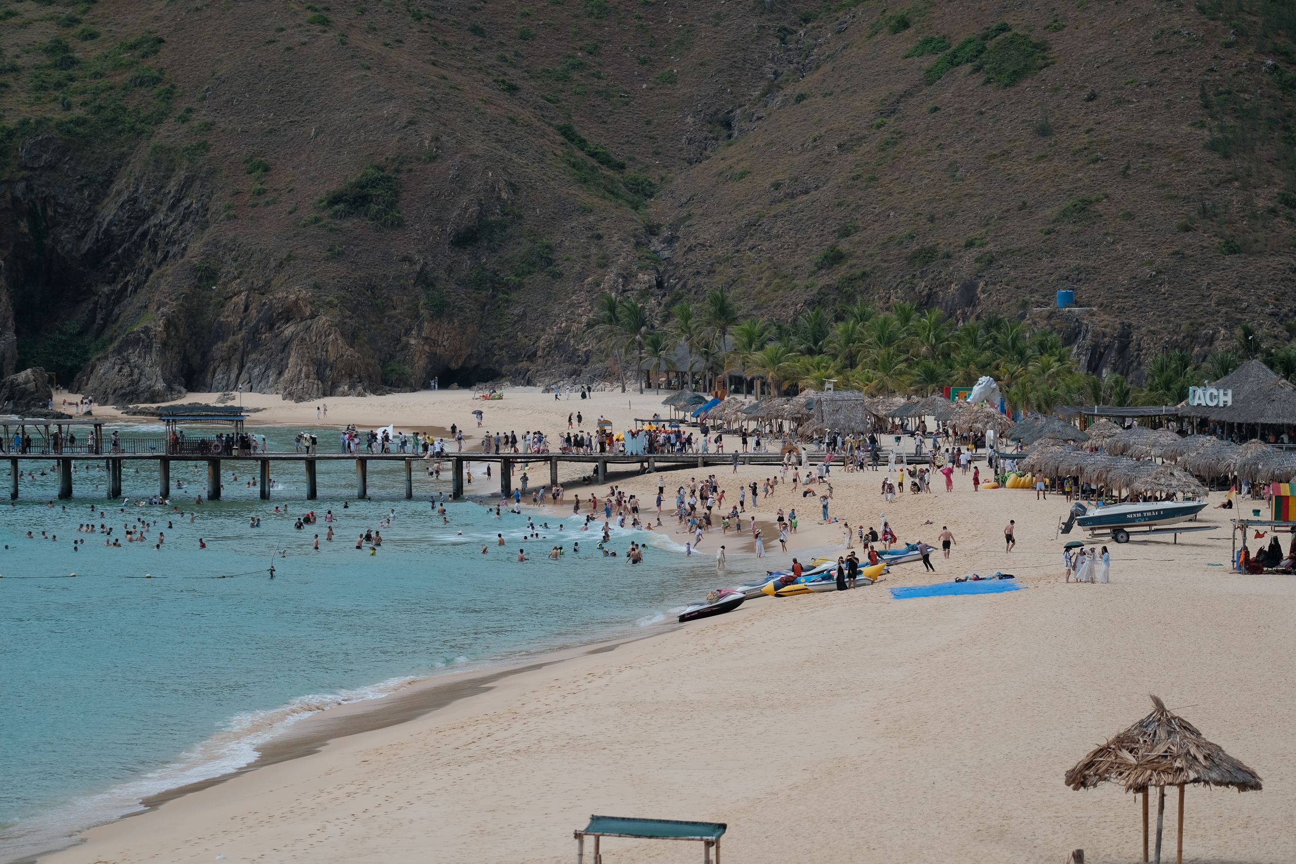 A vibrant tropical beach scene with people enjoying water activities and beachside relaxation.