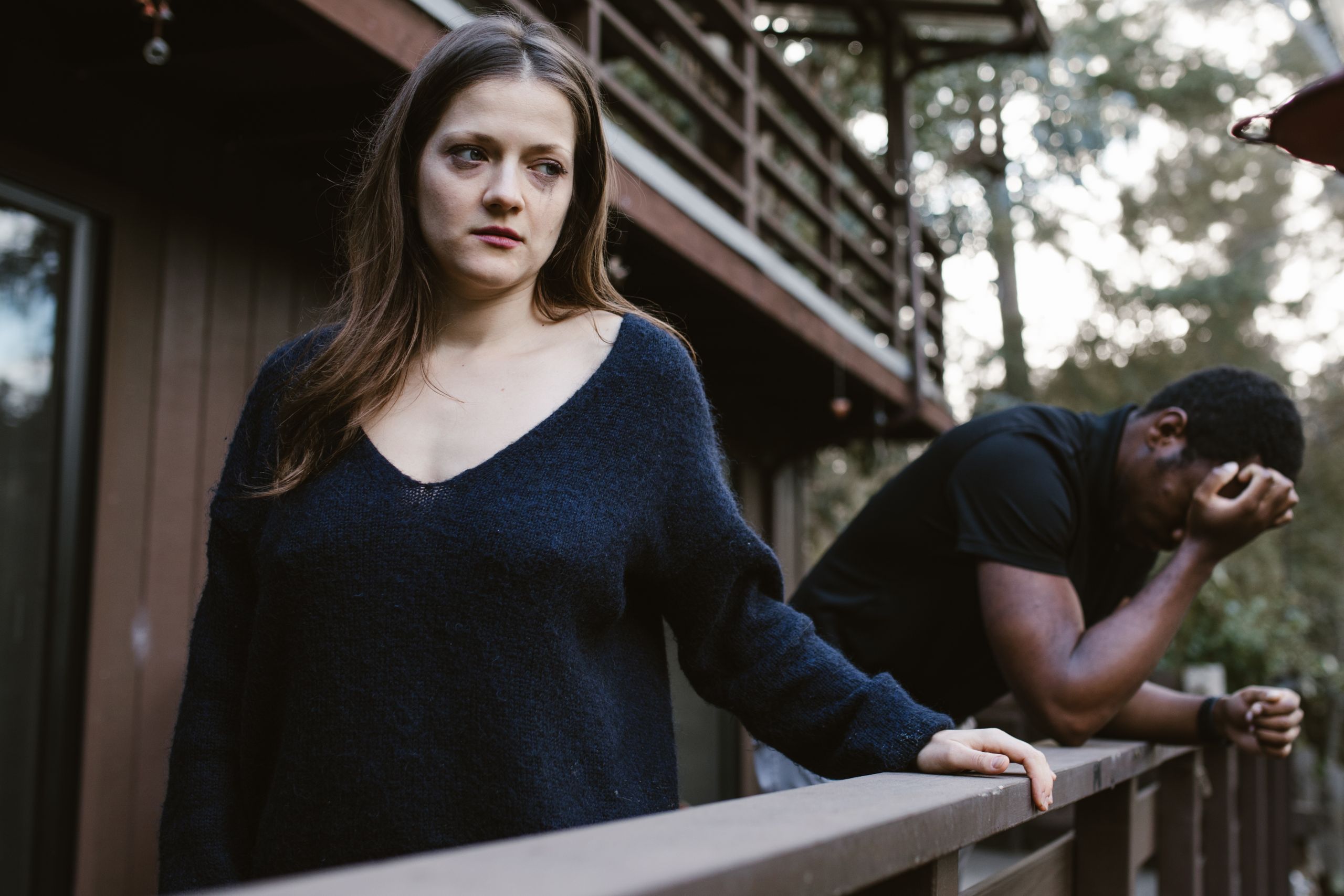 A woman and a man in emotional distress on a balcony, expressing tension.