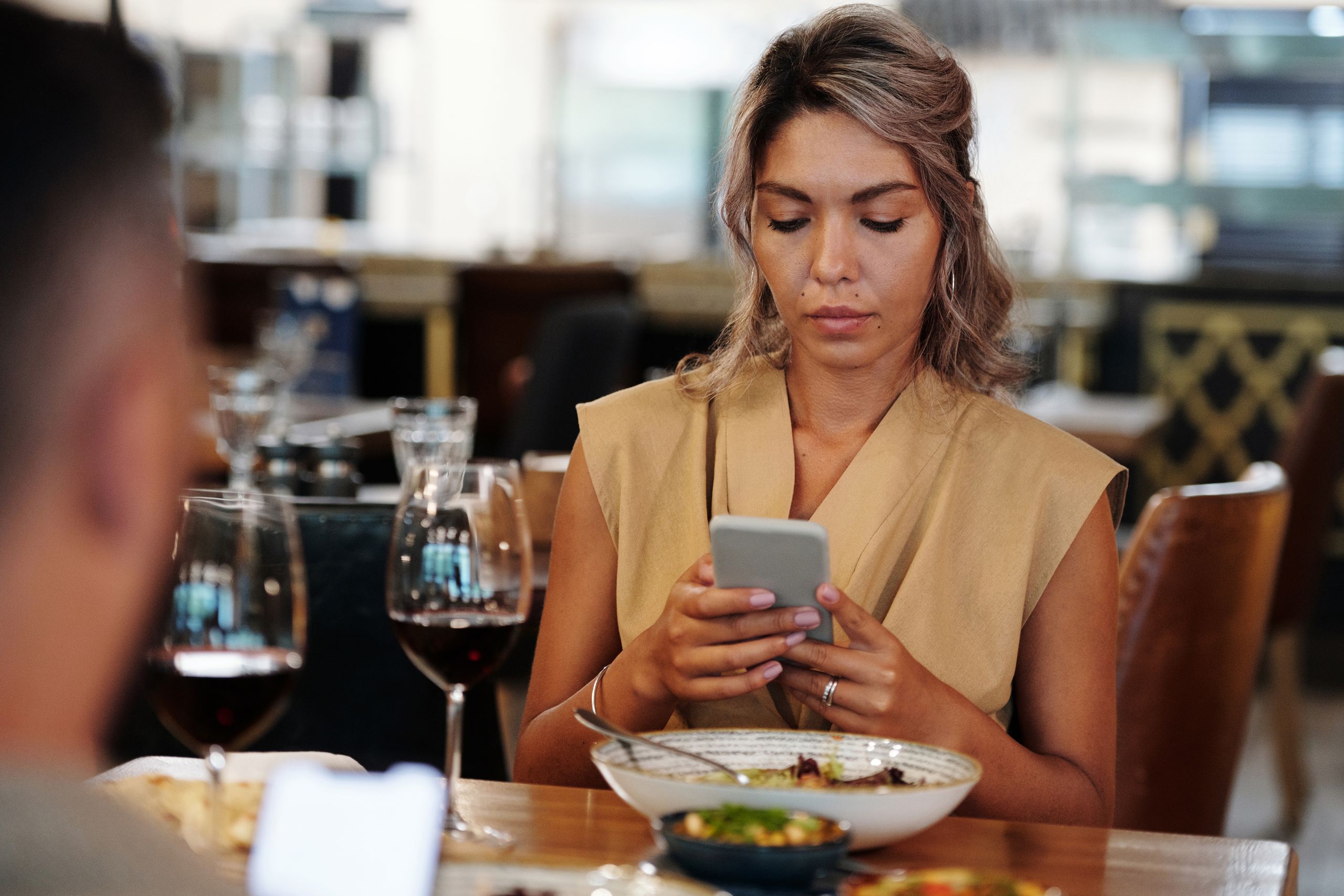 A woman focused on her smartphone while dining in a restaurant.