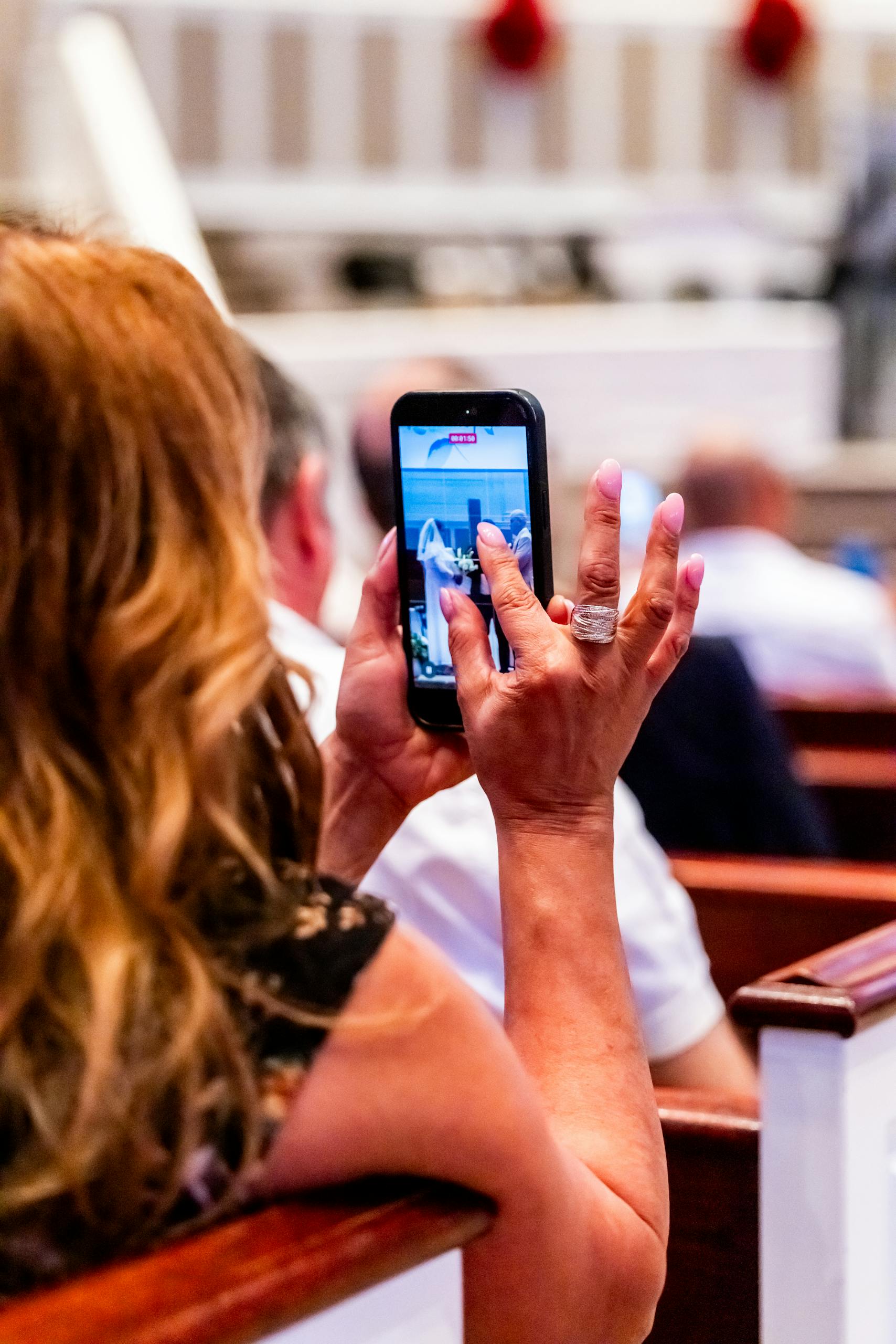 A woman taking a photo with her smartphone during a church event, showcasing modern technology in traditional settings.