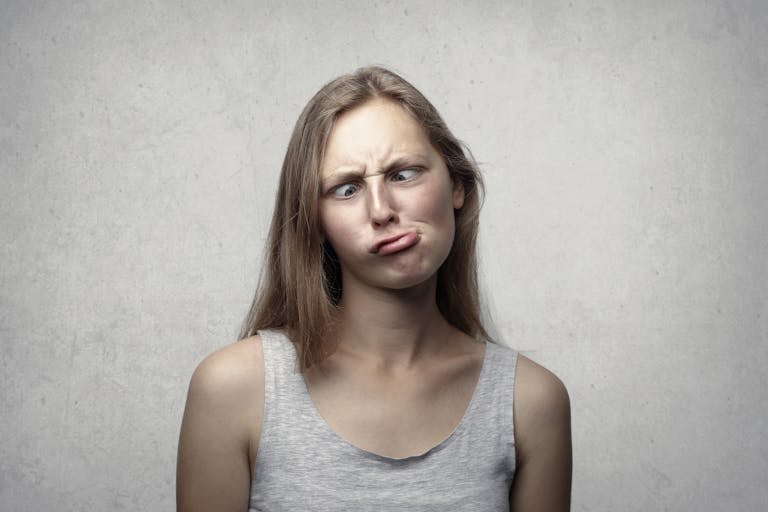 A woman with long hair making a silly expression, adding humor to an otherwise plain gray background.