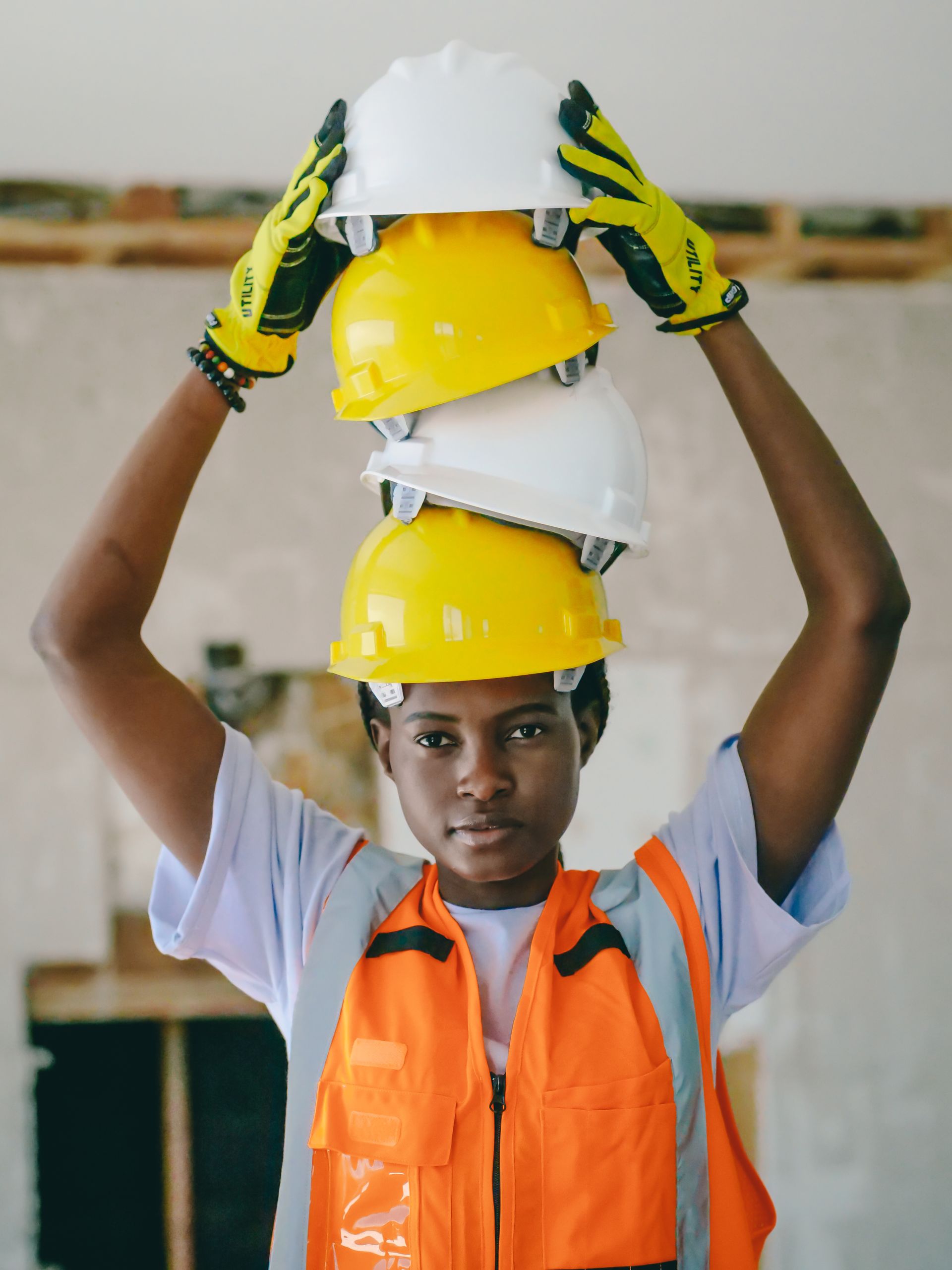 A young engineer skillfully balances safety helmets while wearing protective gear.