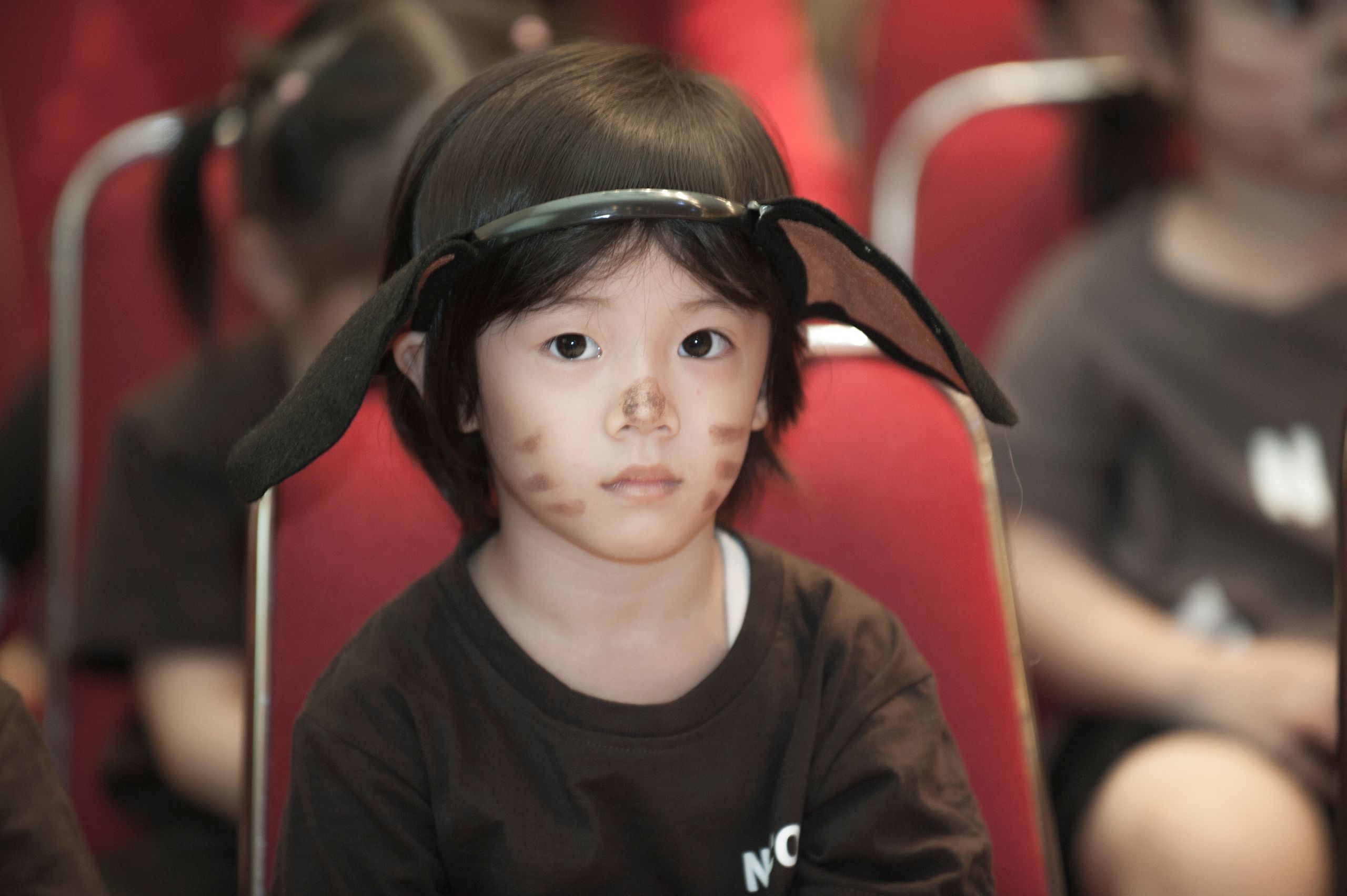 Adorable child wearing face paint and costume sitting indoors.