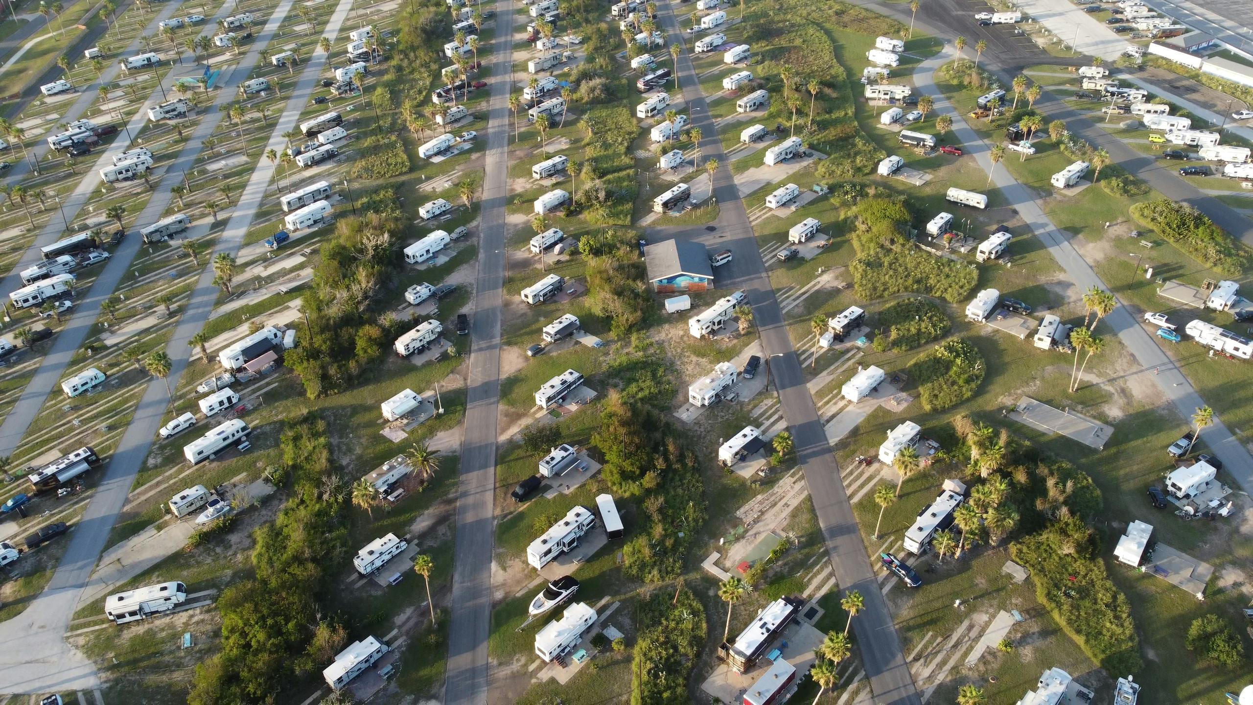 Aerial shot of a lush campsite filled with RVs and trailers during the day.