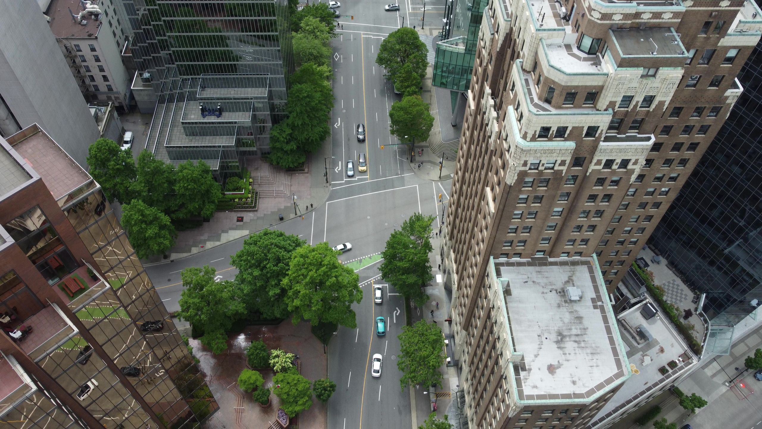 Aerial view of a city intersection surrounded by skyscrapers and greenery, showcasing urban architecture.