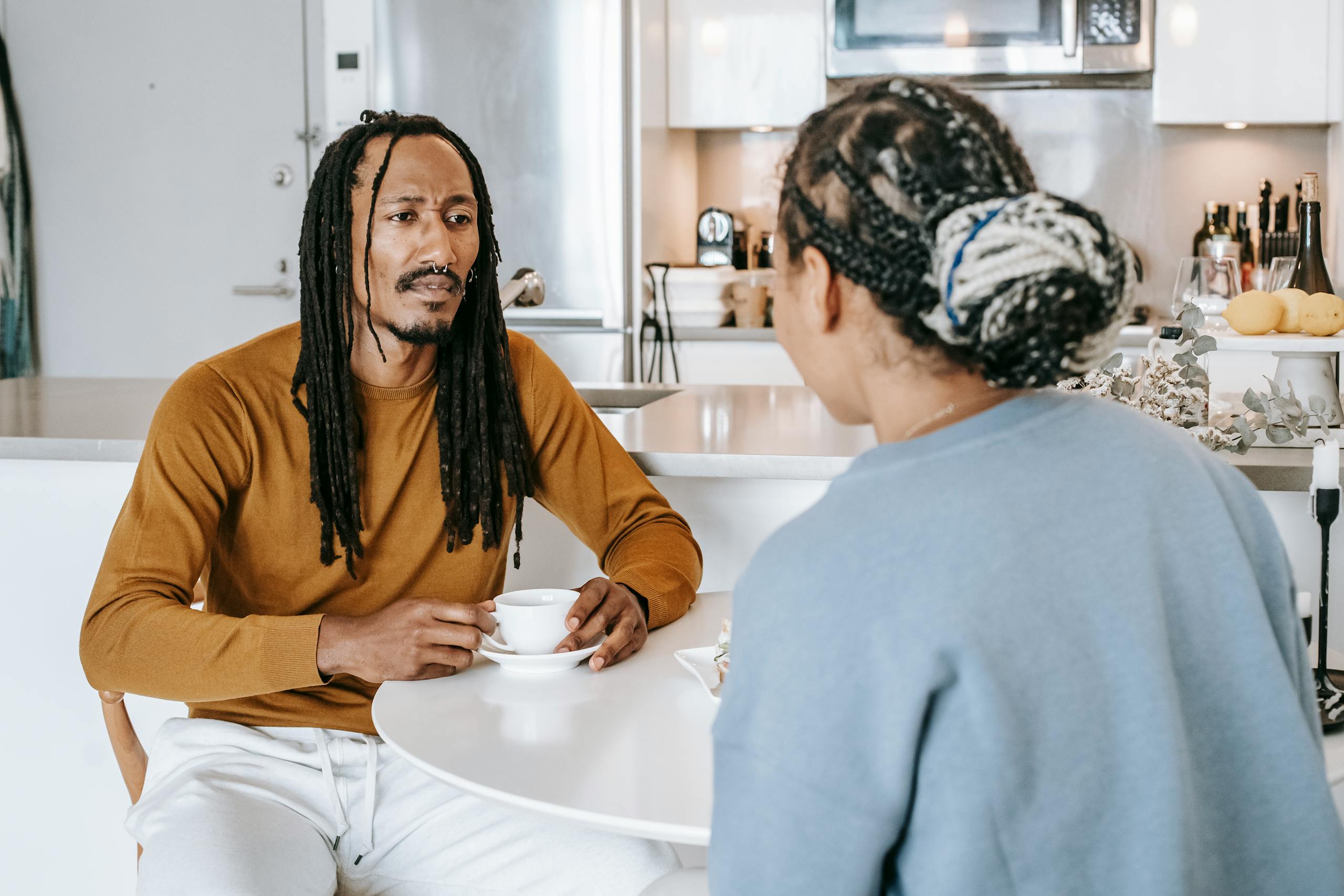 African American male having conversation with African American female in kitchen while having breakfast