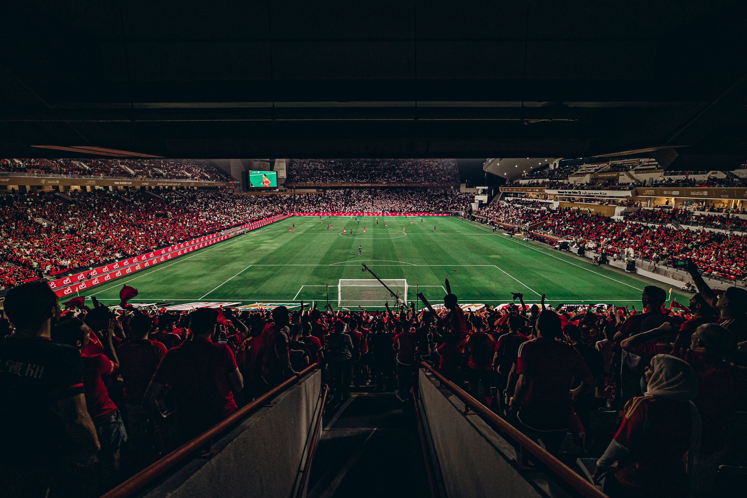 An exciting football match with passionate fans filling the stadium under bright lights, capturing sports energy.