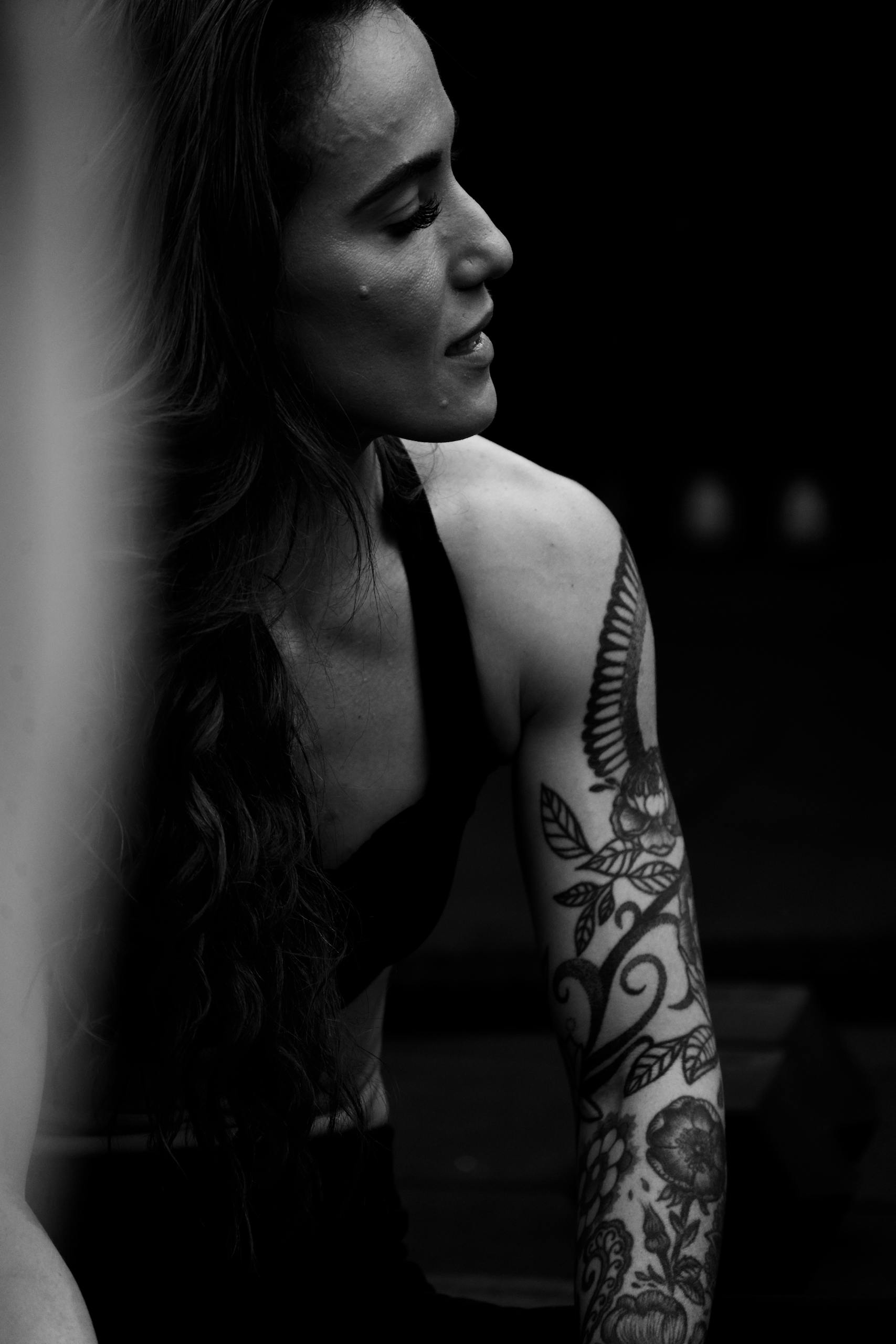 Artistic black and white portrait highlighting intricate tattoos on a woman's arm.
